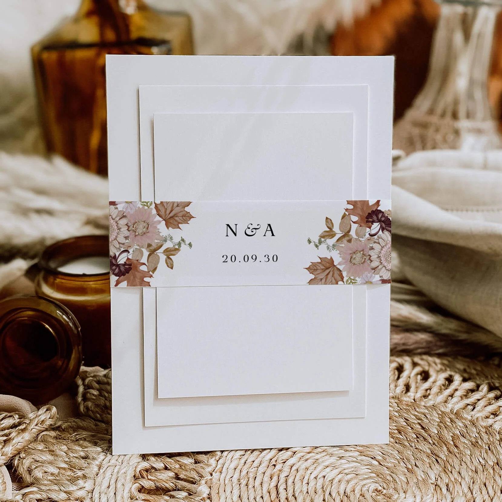 Autumn personalised wedding belly bands with watercolour autumn leaves and floral illustration wrapped around wedding invitations