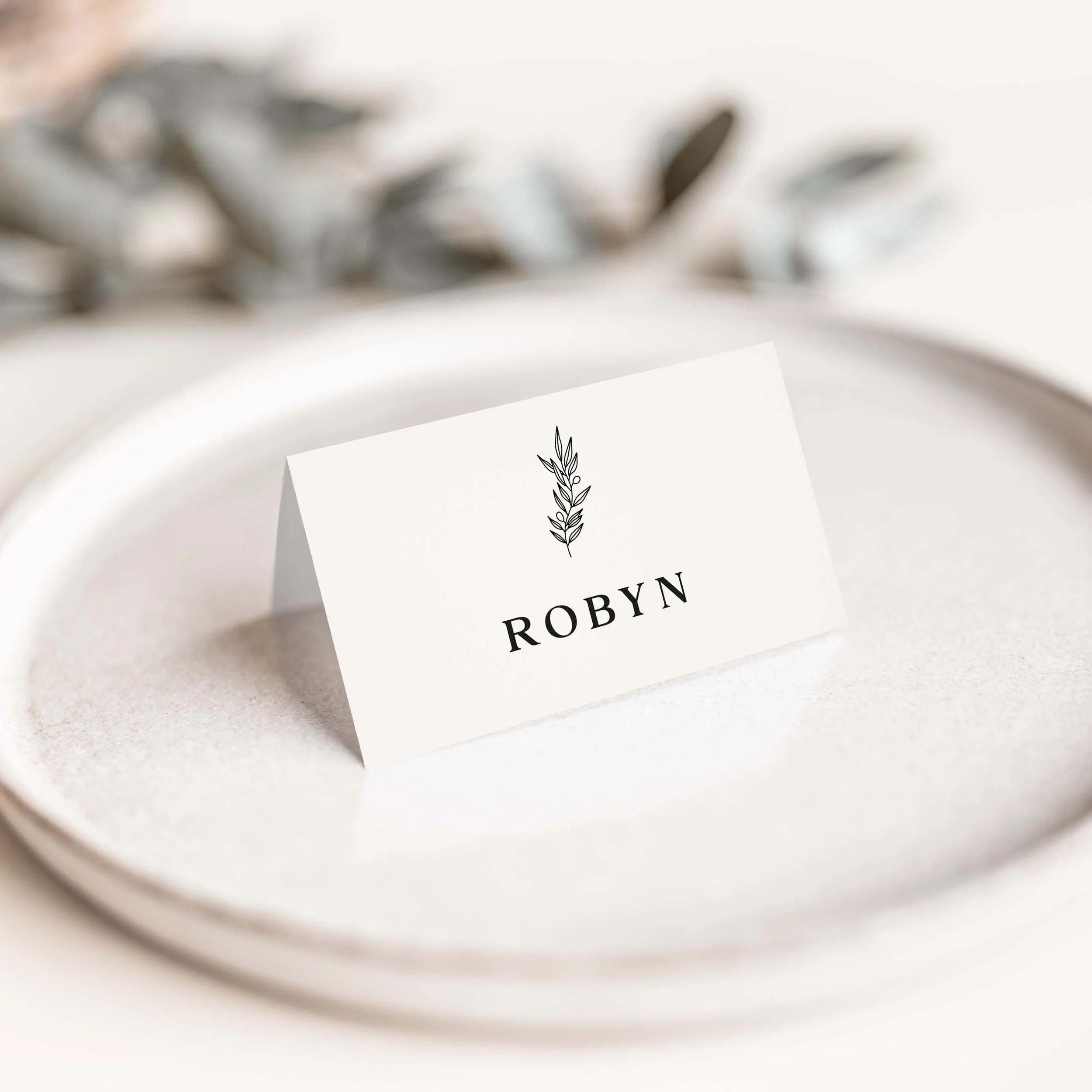 Minimalist wedding place card with small botanical motif and serif font