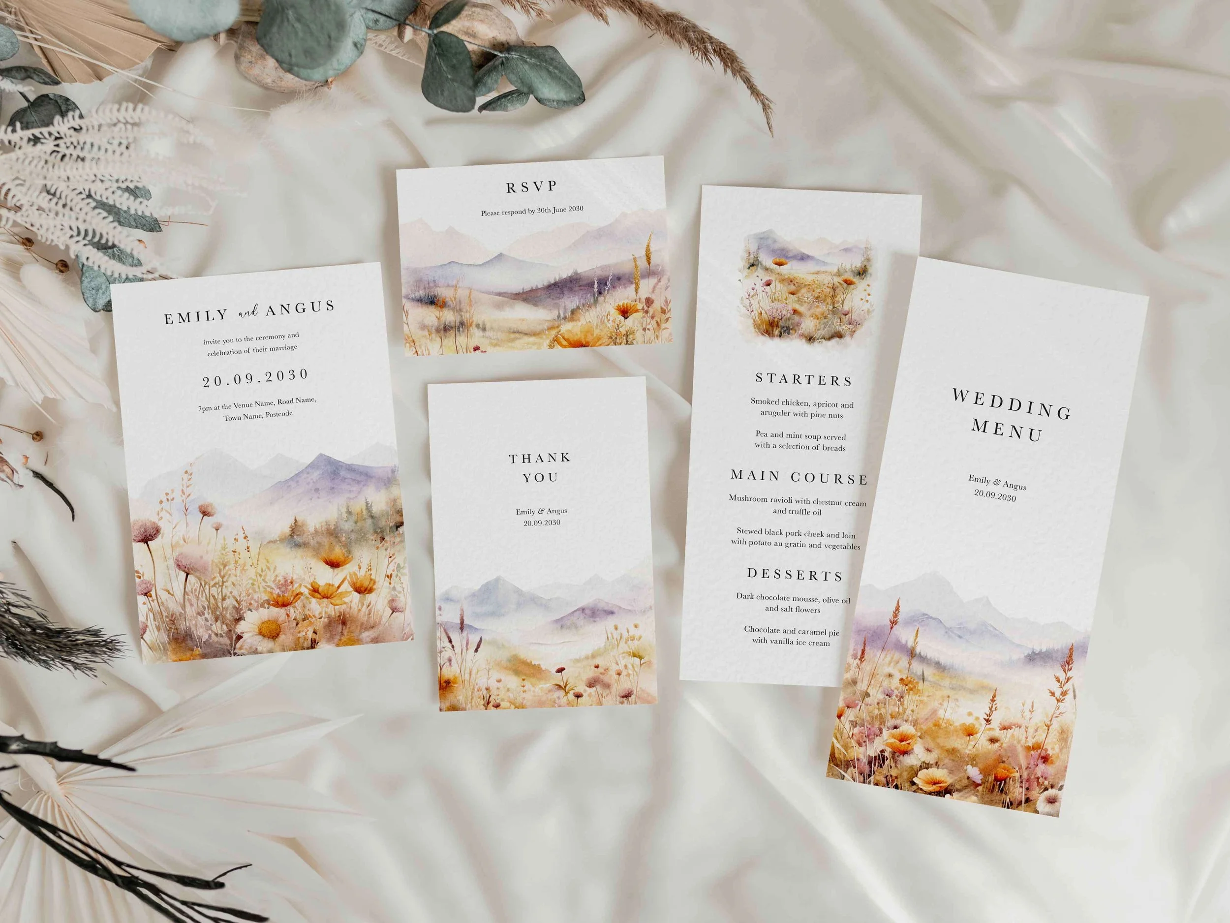 Full Scenic wedding stationery suite flat lay showing invitations, RSVP cards and coordinating pieces with a watercolour purple mountain and wildflower landscape