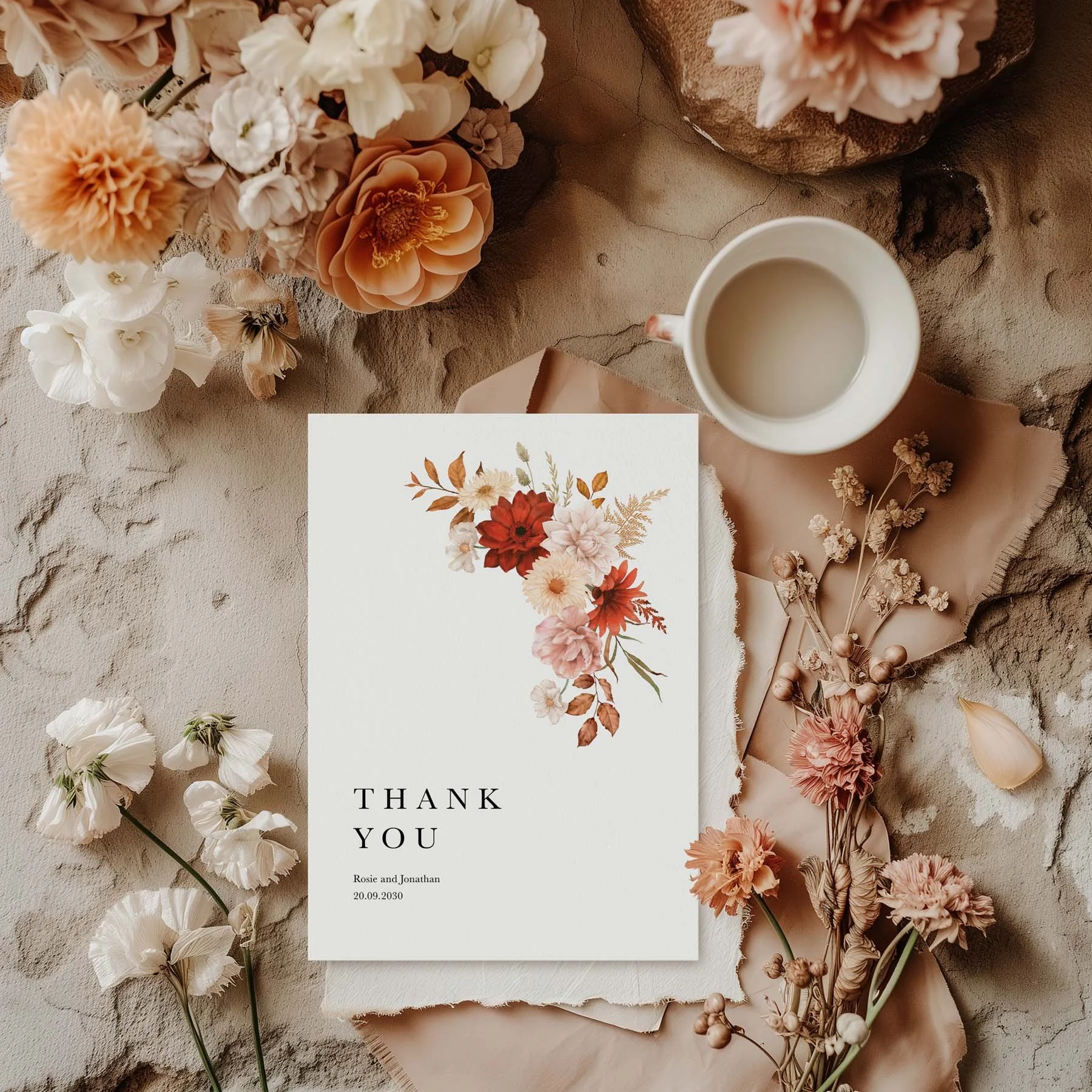 Rustic wedding thank you card with a crimson dahlia and cream floral design, styled with dried flowers and a white cup on a neutral background
