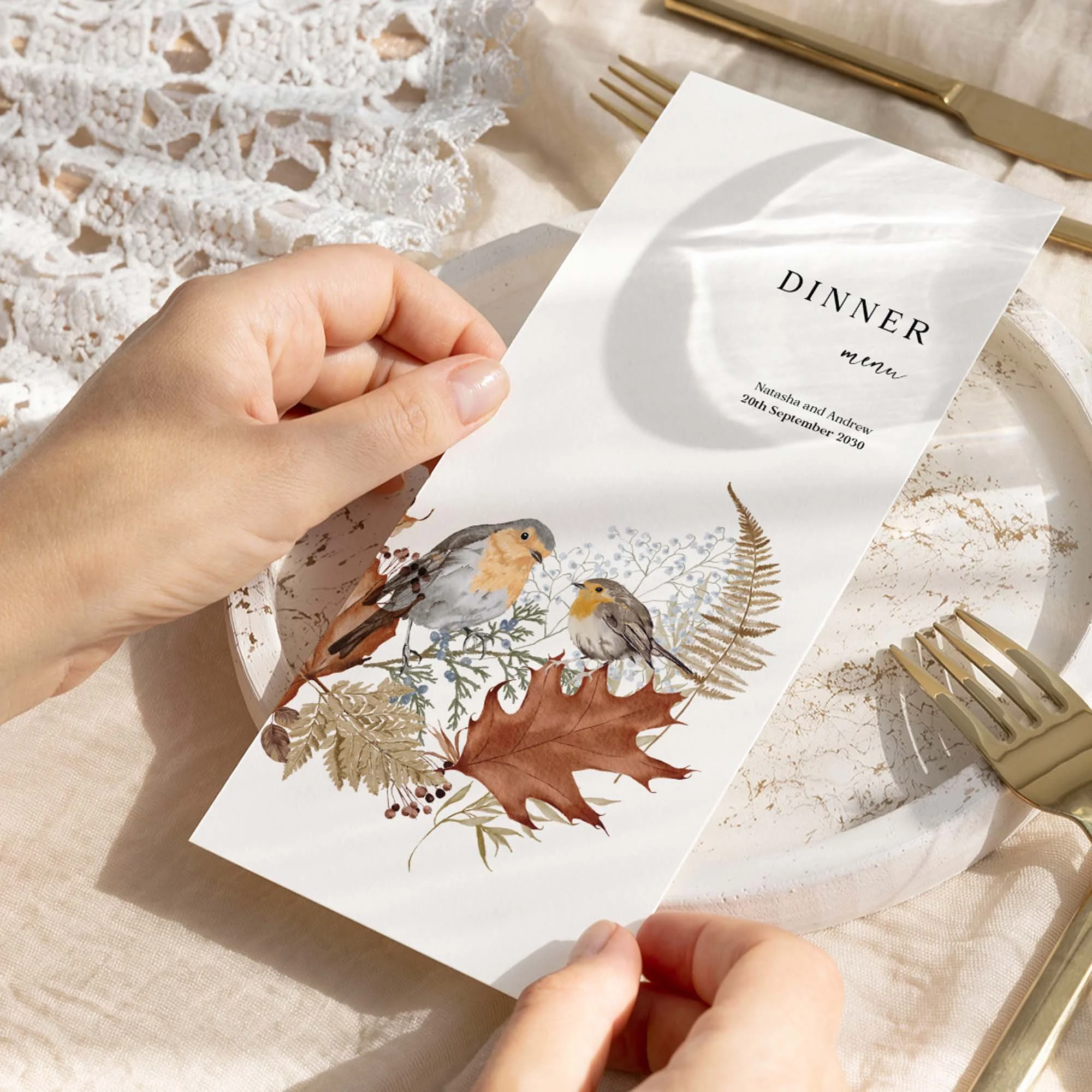 Hand holding an Autumn wedding breakfast menu card featuring a hand-painted robin with autumn botanical illustration