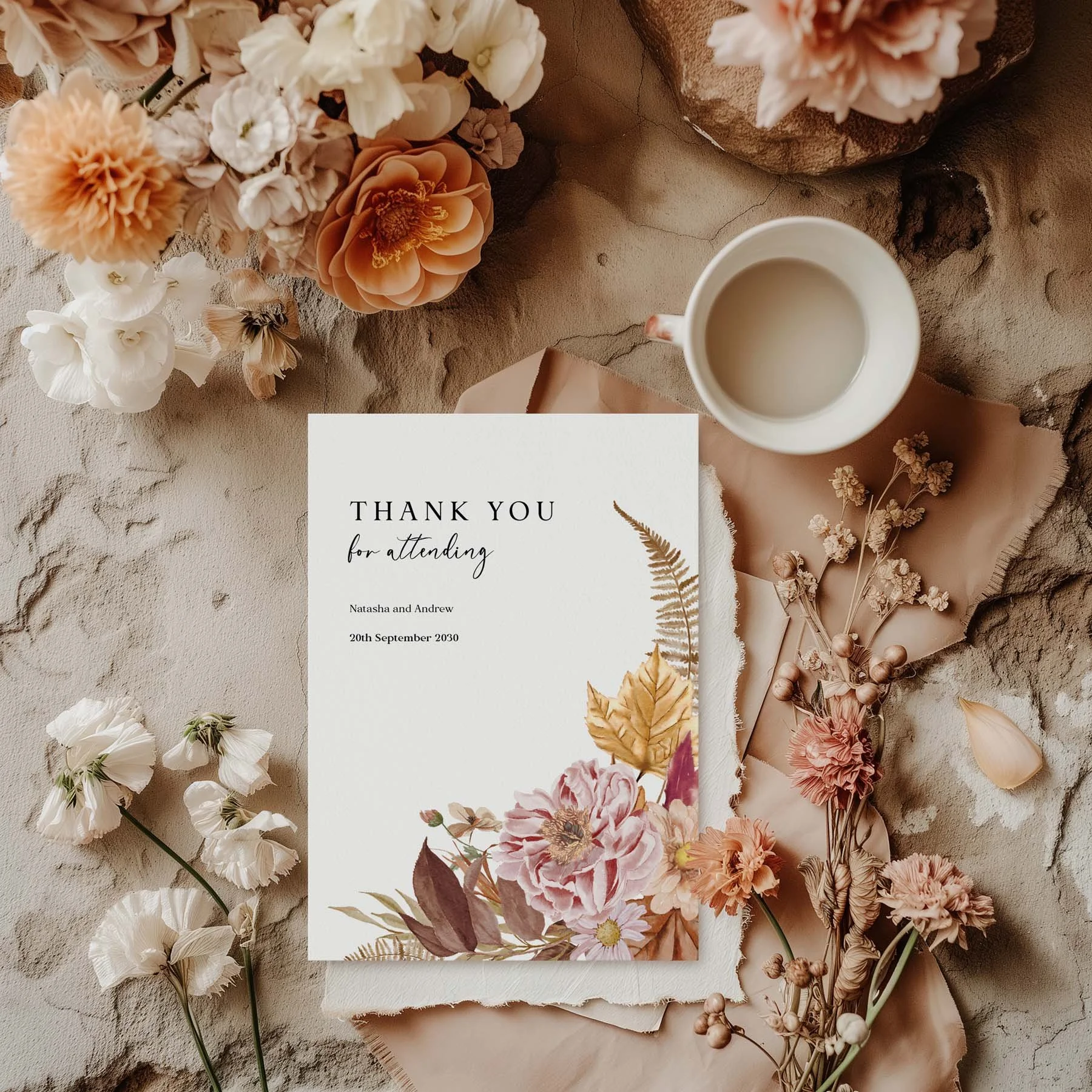 Autumn wedding thank you card with a botanical bouquet of dahlias, golden ferns and autumn leaves, styled with dried flowers and a white cup on a neutral background