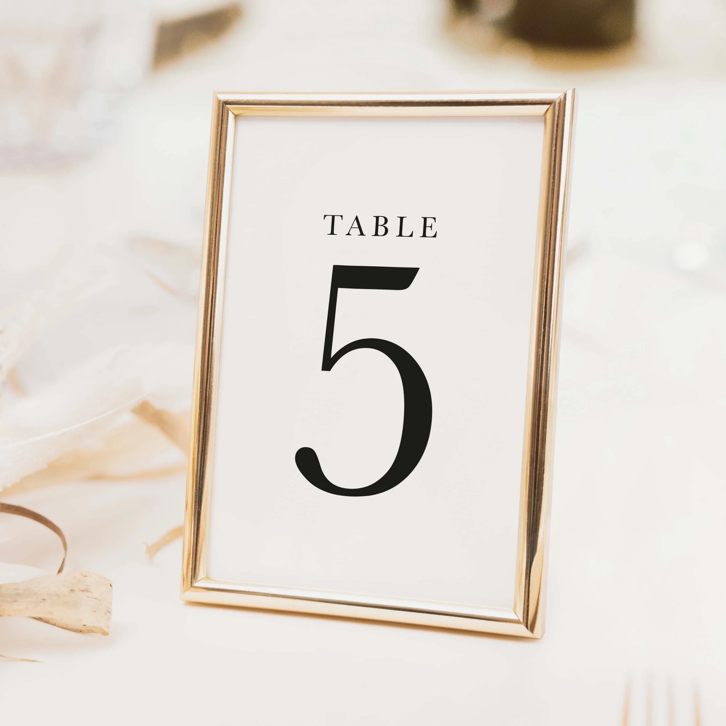 Minimalist typographic wedding table number with large clean bold numeral and spaced lettering on luxury off-white card
