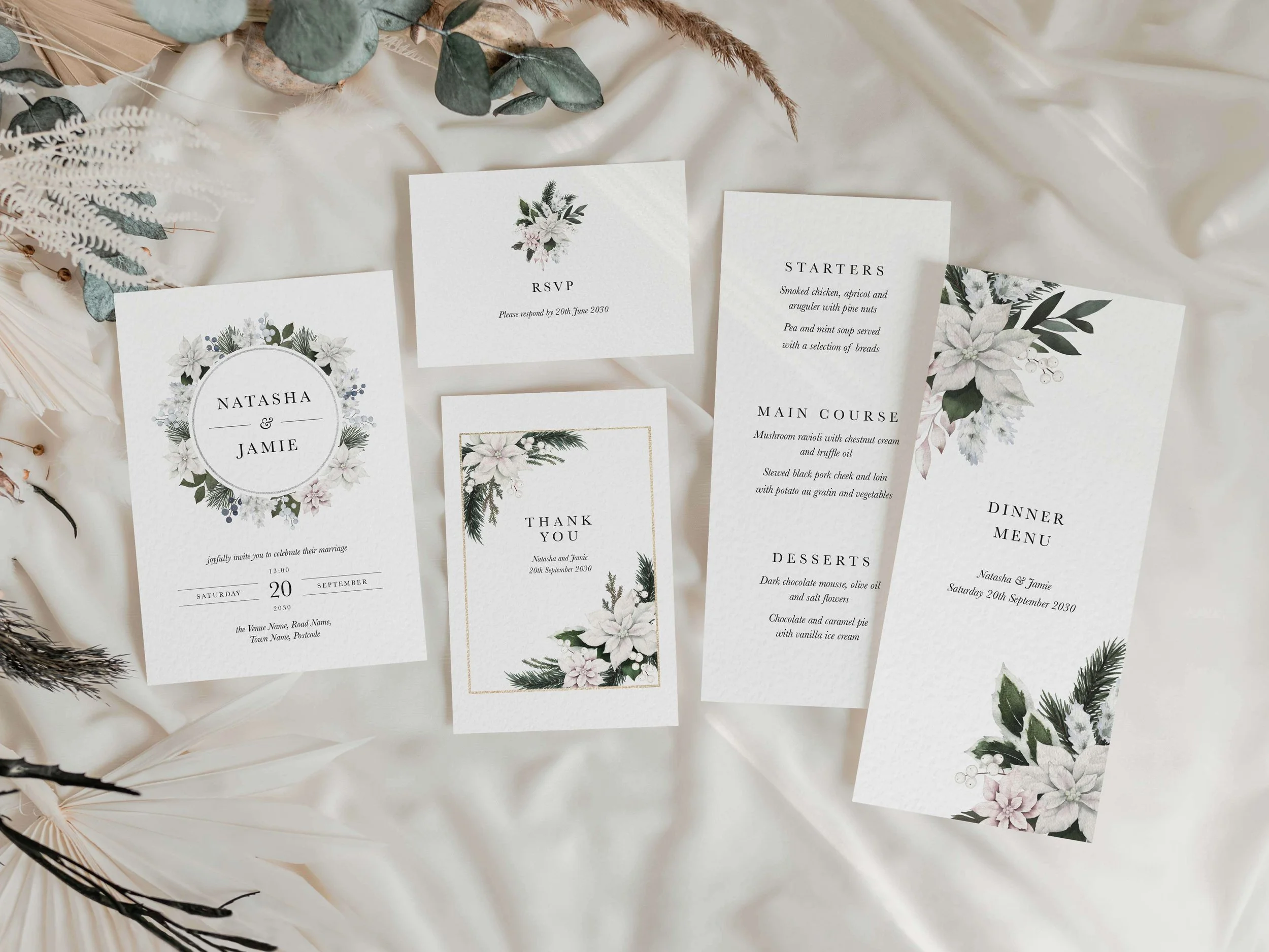 Full Winter Frost wedding stationery suite flat lay showing invitations, RSVP cards and coordinating pieces with white poinsettia botanical wreath design