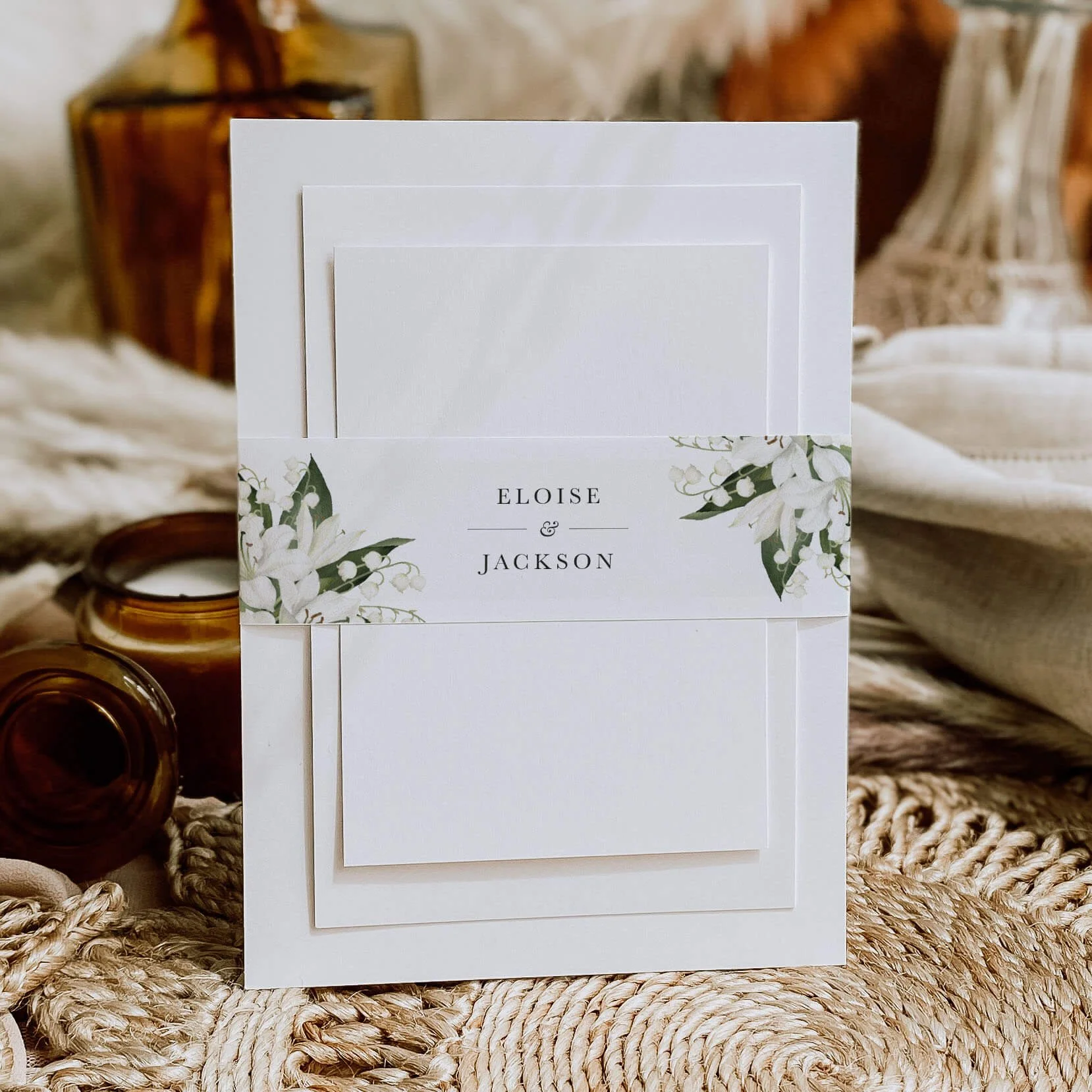 Garden personalised wedding belly bands with lily of the valley watercolour illustration and serif names wrapped around wedding invitations