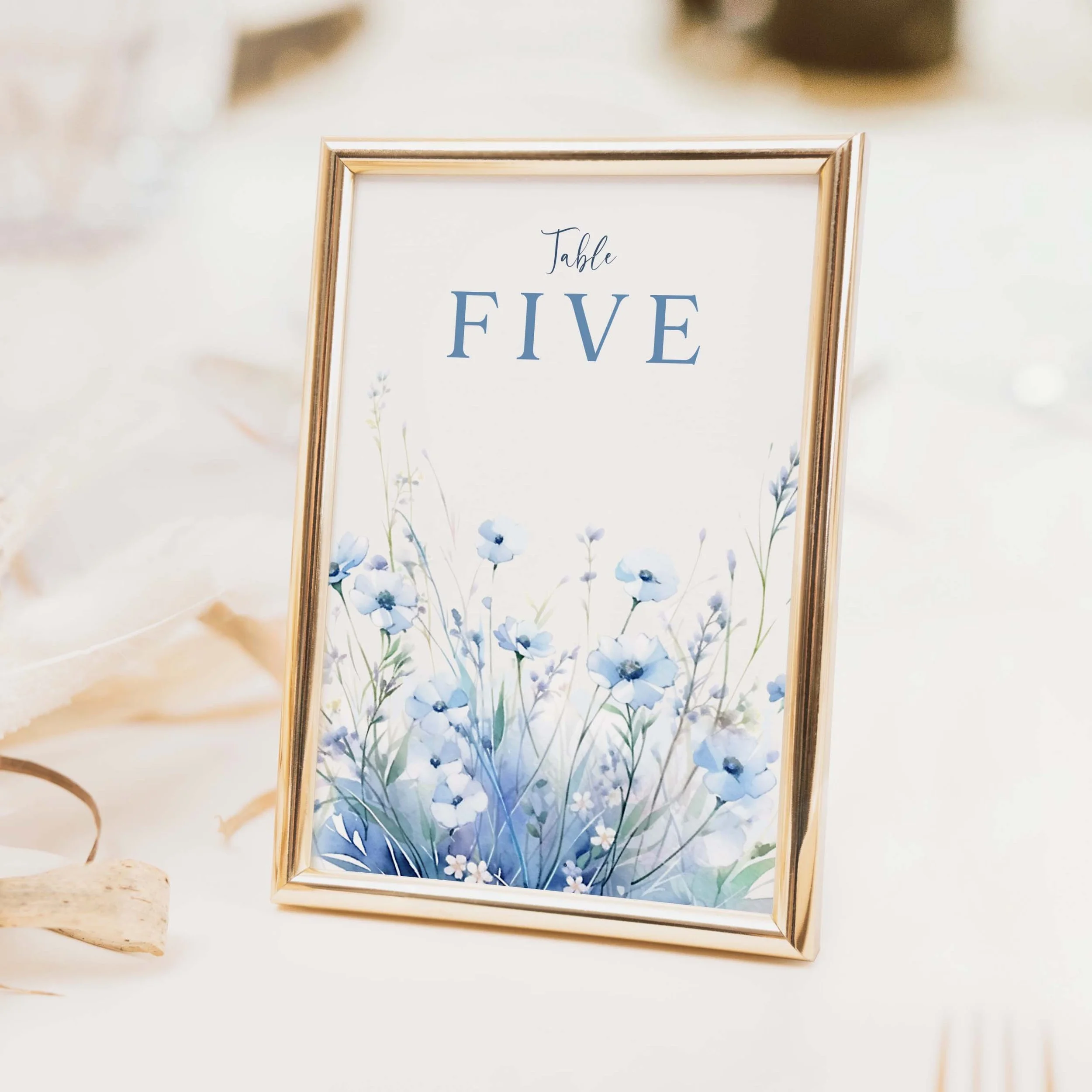 Field Dusty Blue wedding table number with blue watercolour wildflower meadow illustration and clean typography on luxury off-white card