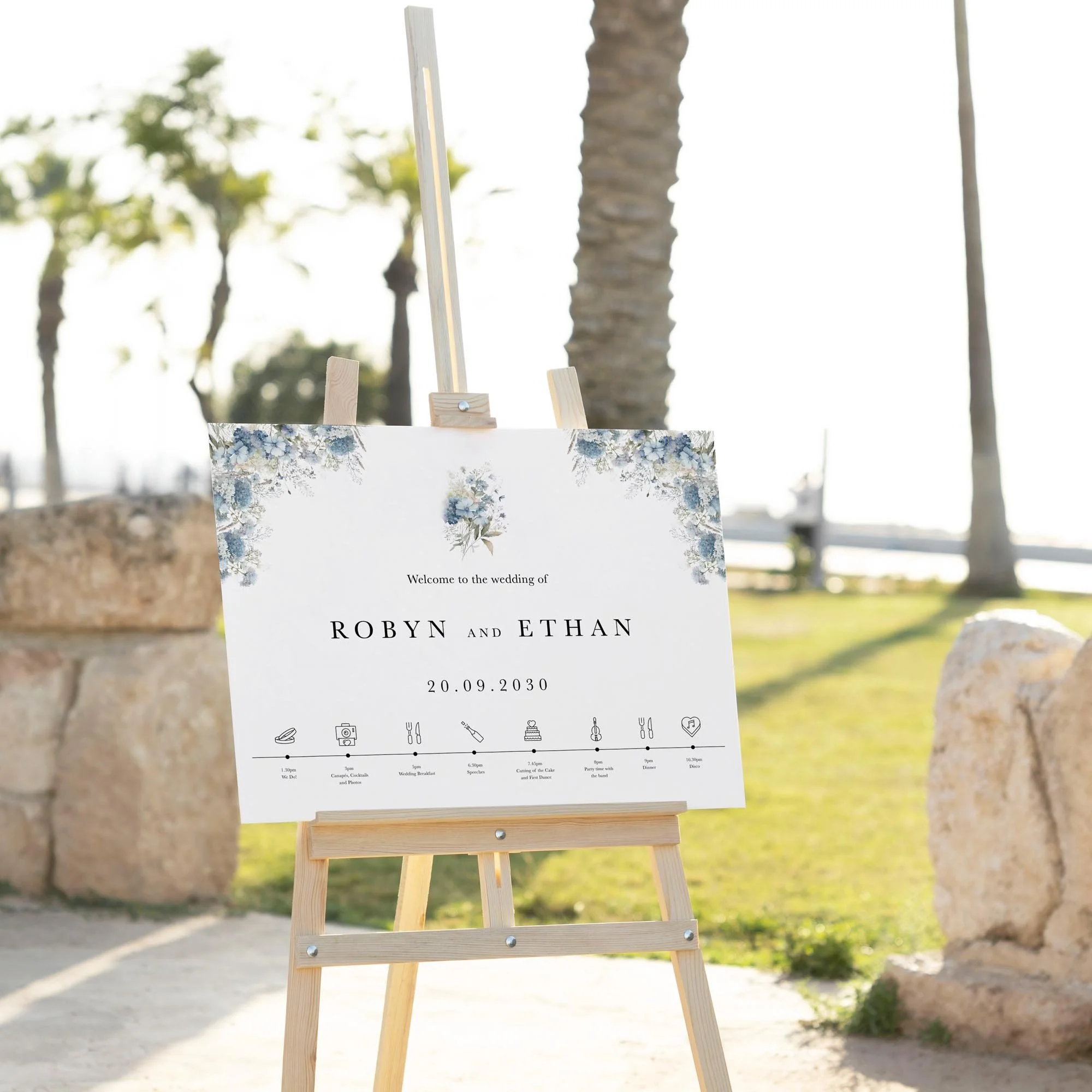 Dusty Blue Floral wedding welcome sign displayed outdoors at a wedding venue on an easel