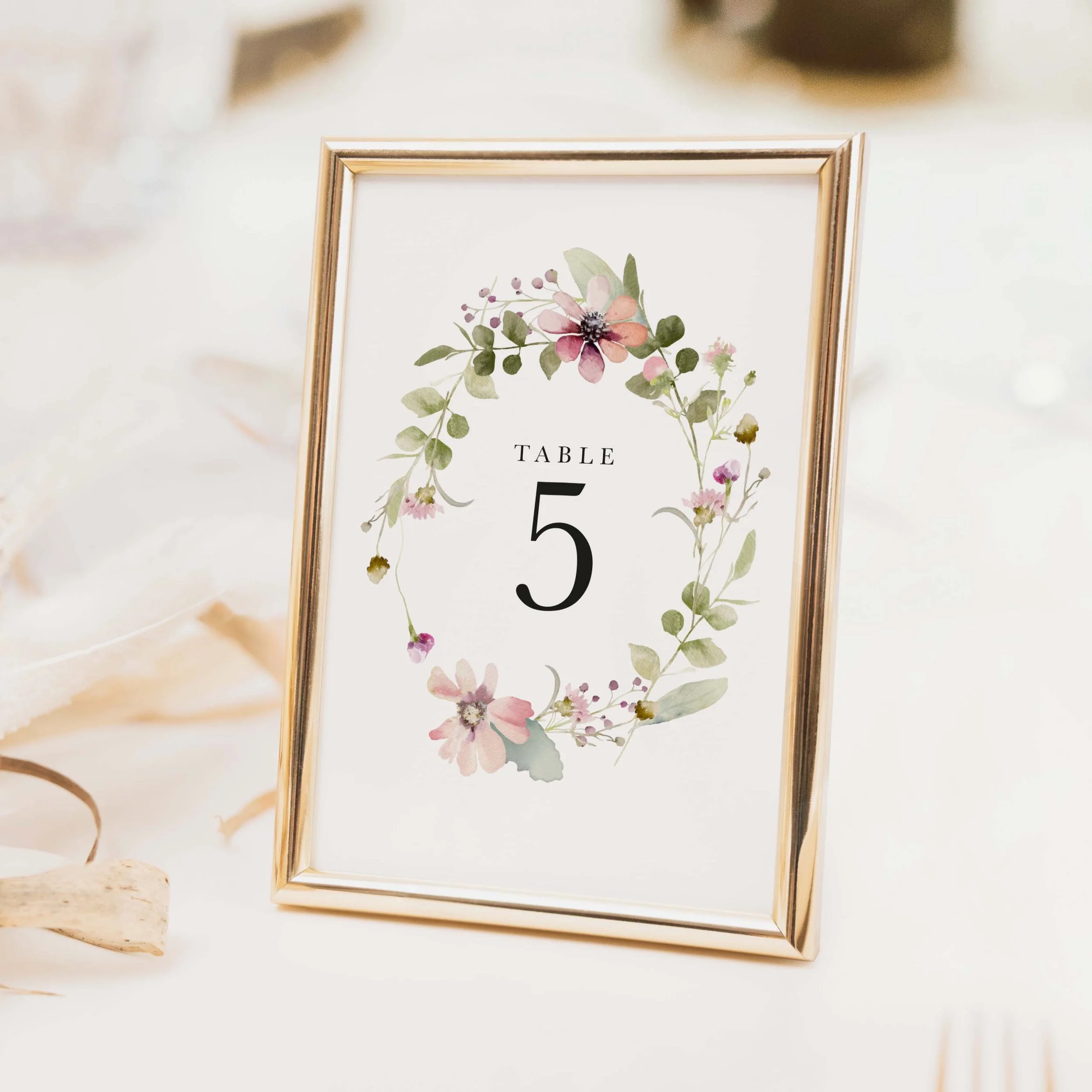 Bloom wedding table number with mixed floral wreath illustration in soft pink, purple and green tones with classic typography printed on luxury off-white textured card