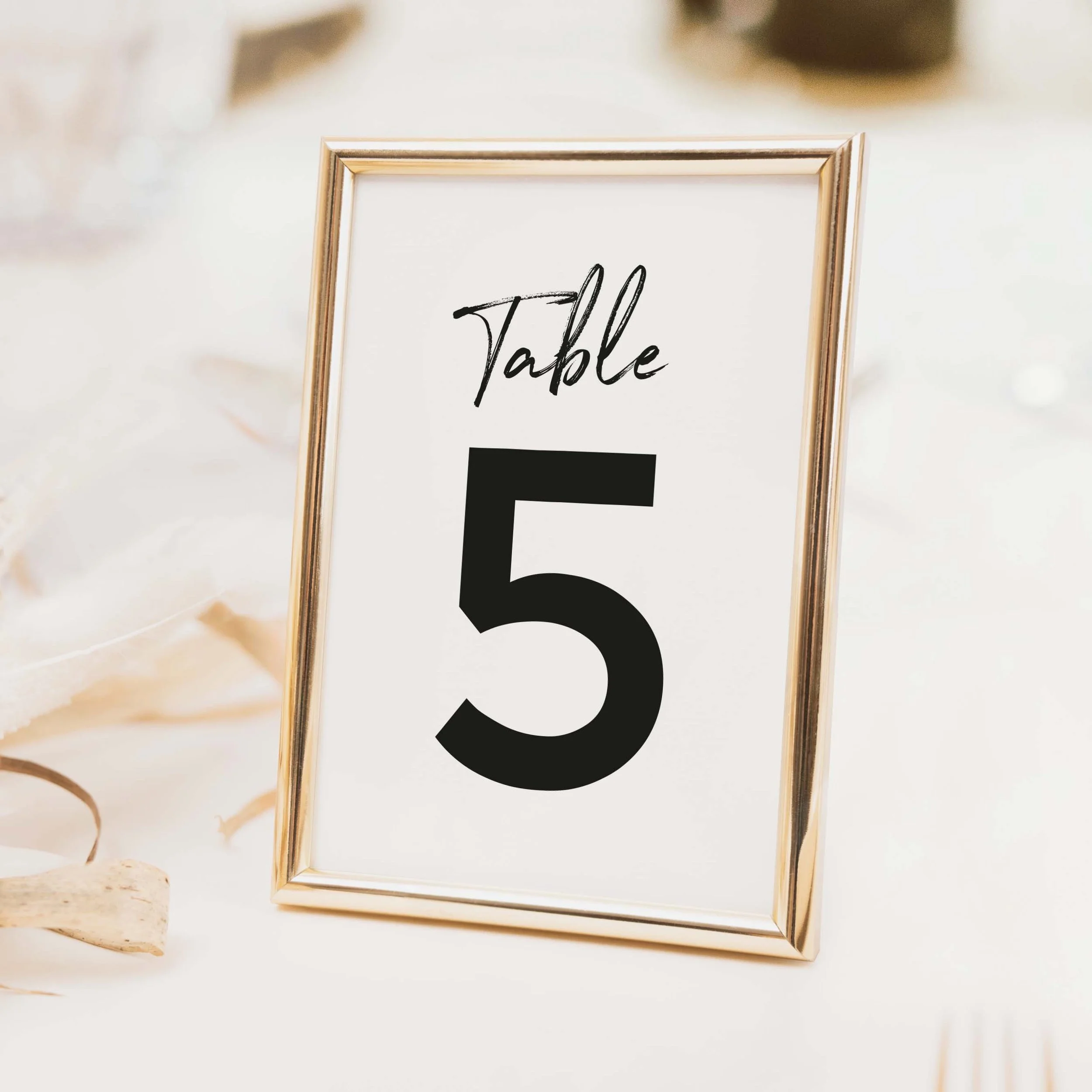Signature wedding table number with large bold clean numeral and small calligraphy script label in pure typographic style on luxury off-white card