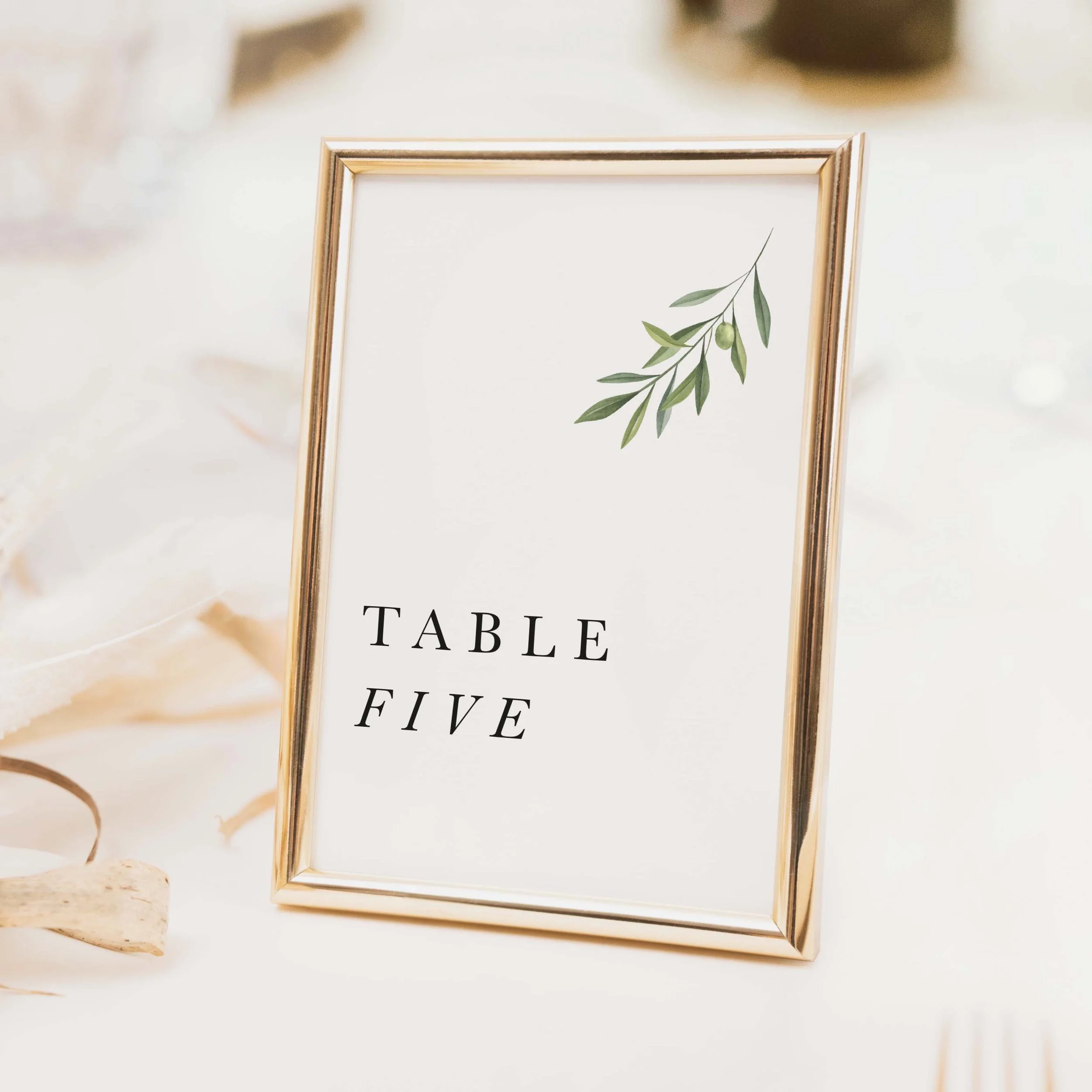 Olive wedding table number with delicate olive branch botanical illustration and stacked clean typography on luxury off-white card