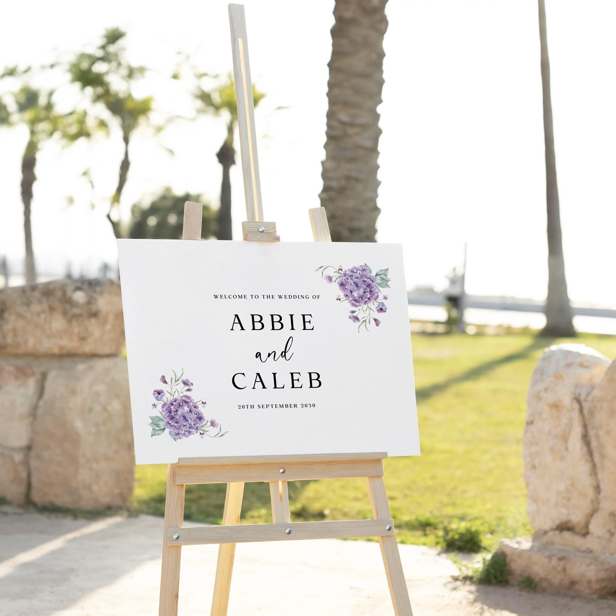 Purple Hydrangea wedding welcome sign displayed outdoors at a wedding venue on an easel