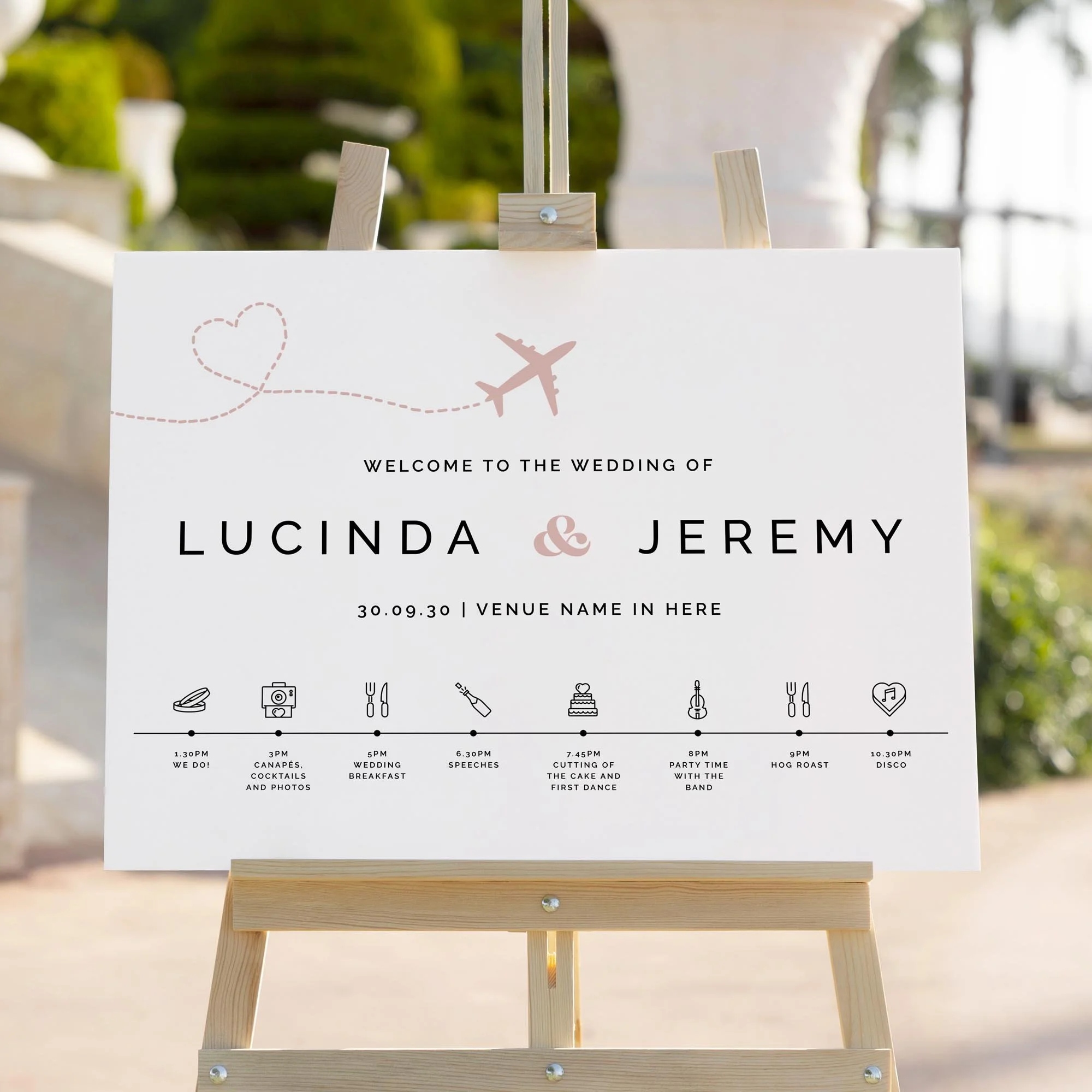 Pink travel themed wedding welcome sign displaying the order of the day on an easel outside