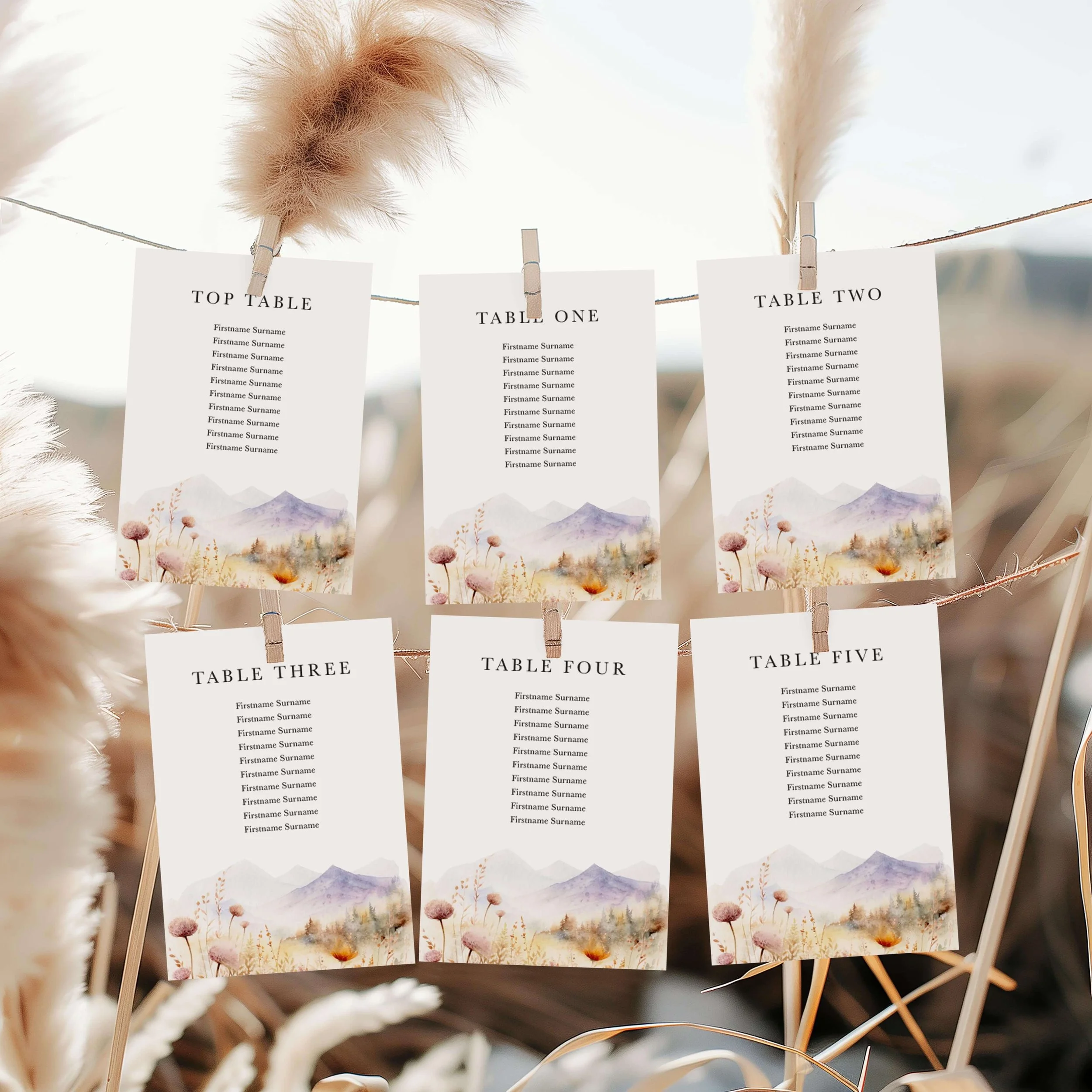 Scenic wedding seating plan displayed on a wooden easel, featuring a watercolour purple mountain and golden meadow design with multiple guest tables