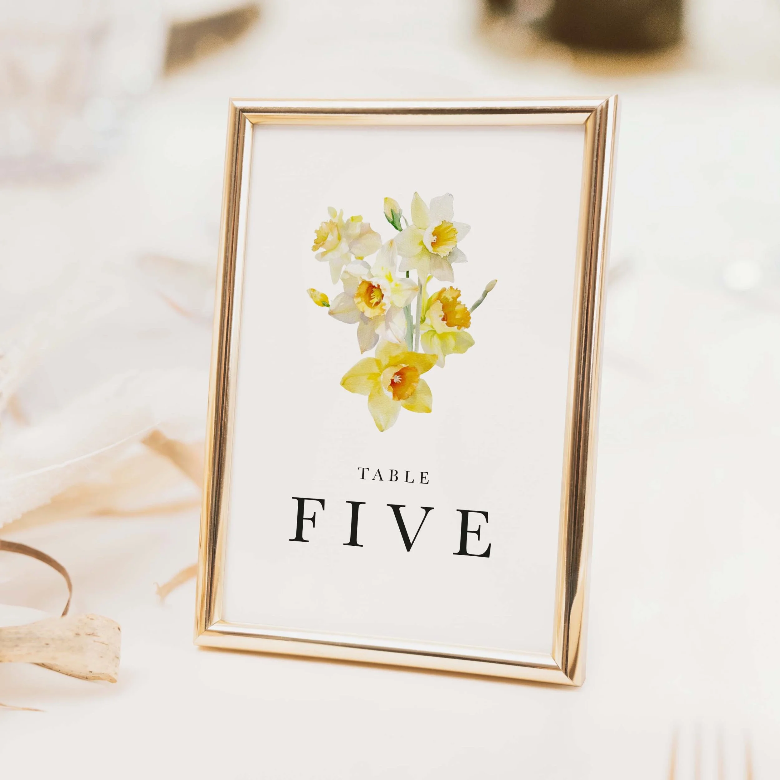 Daffodil wedding table number with yellow botanical daffodil illustration and clean serif typography on luxury off-white card
