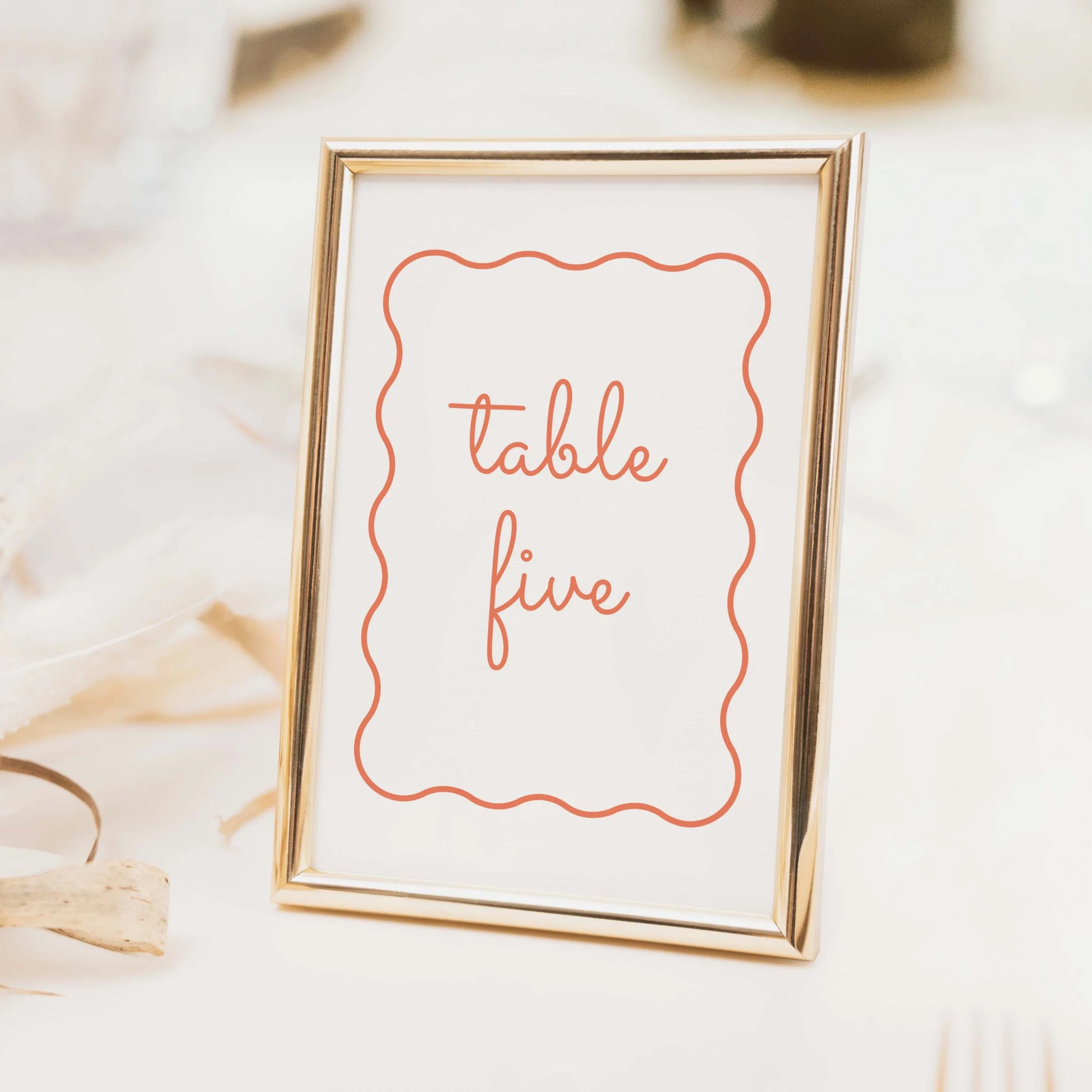 Scallop wedding table number with peach wavy scallop border and flowing calligraphy script table typography on luxury off-white card