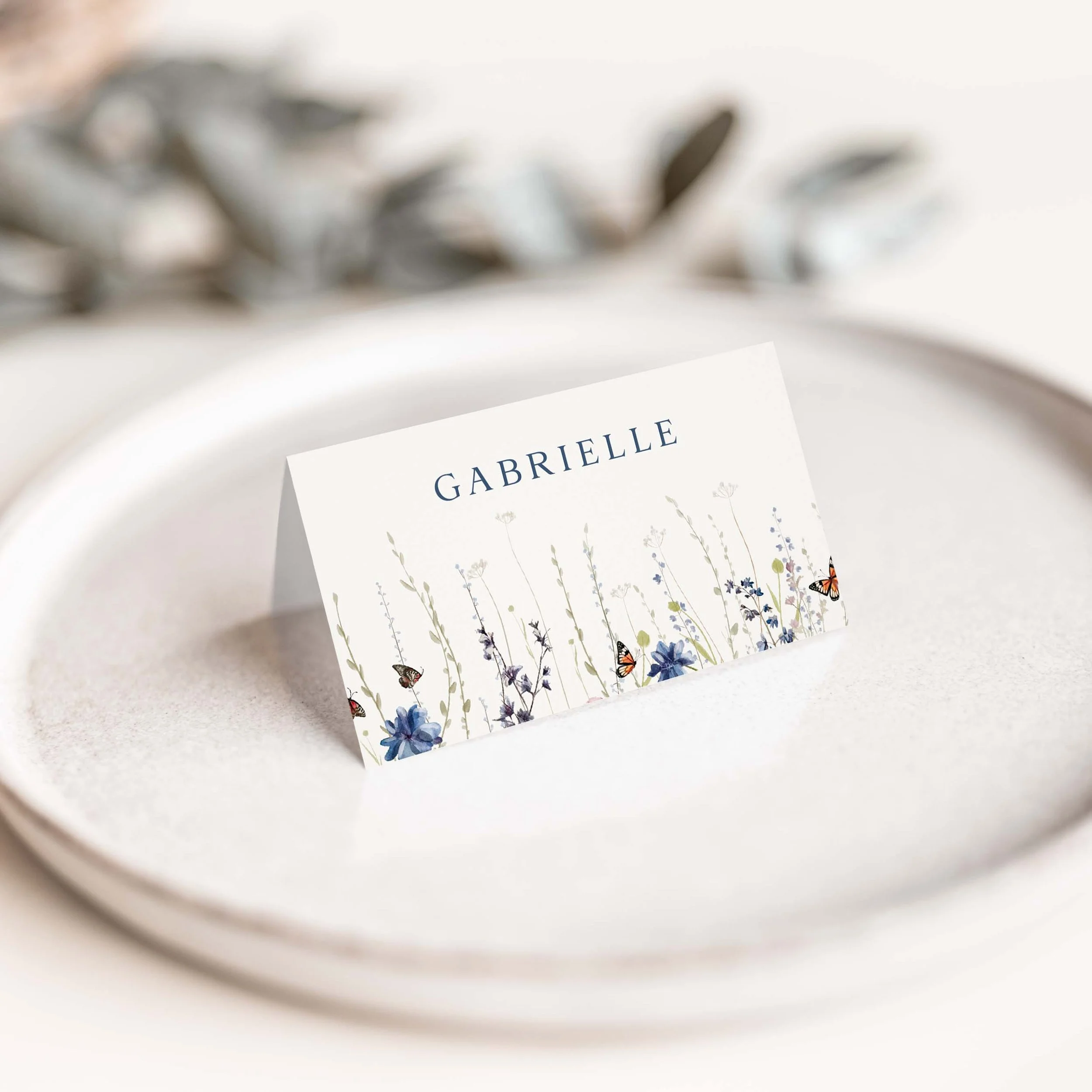 Navy wildflower wedding place card with floral border along the bottom
