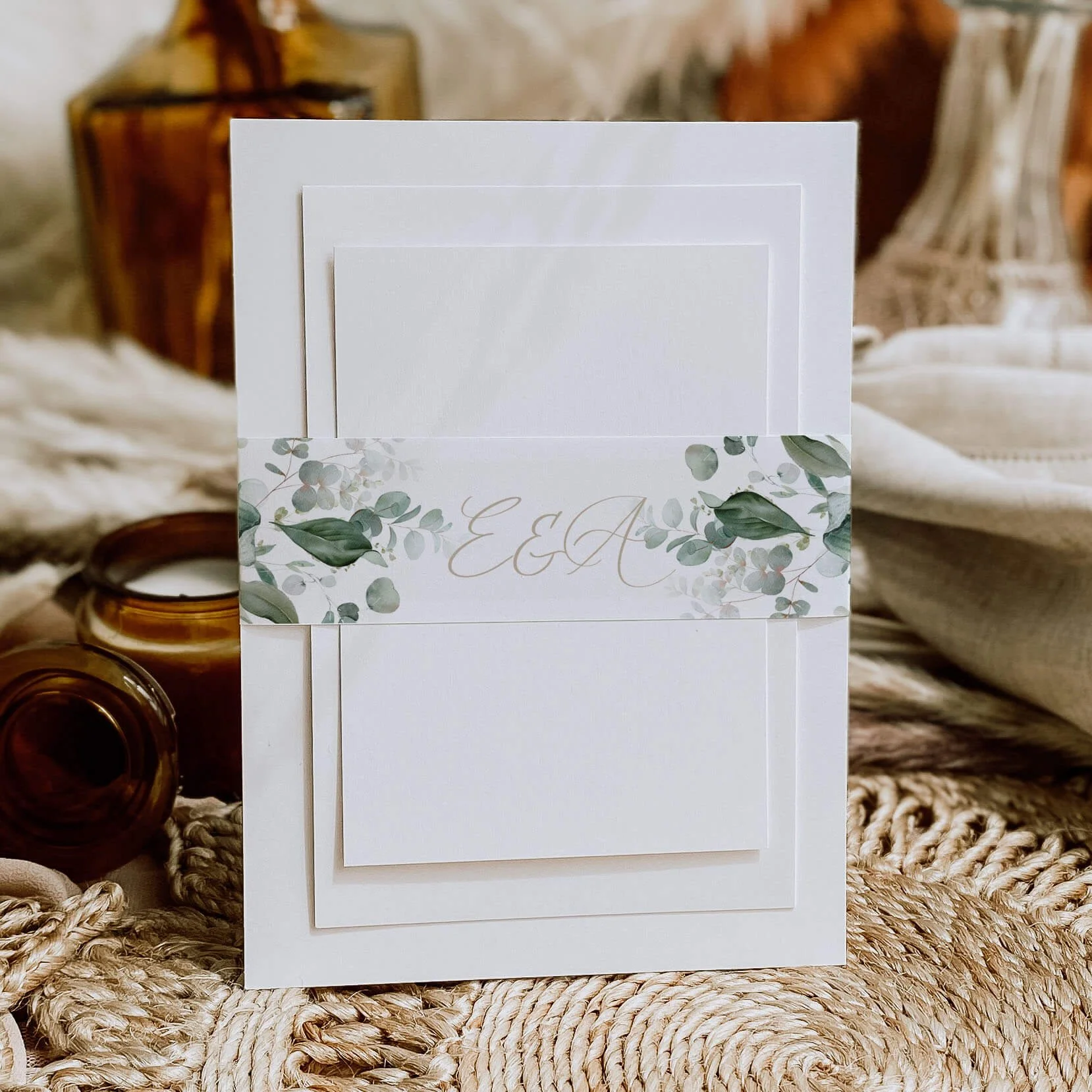Emerald Forest personalised wedding belly bands with large dark green botanical leaf illustration and gold script initials wrapped around wedding invitations