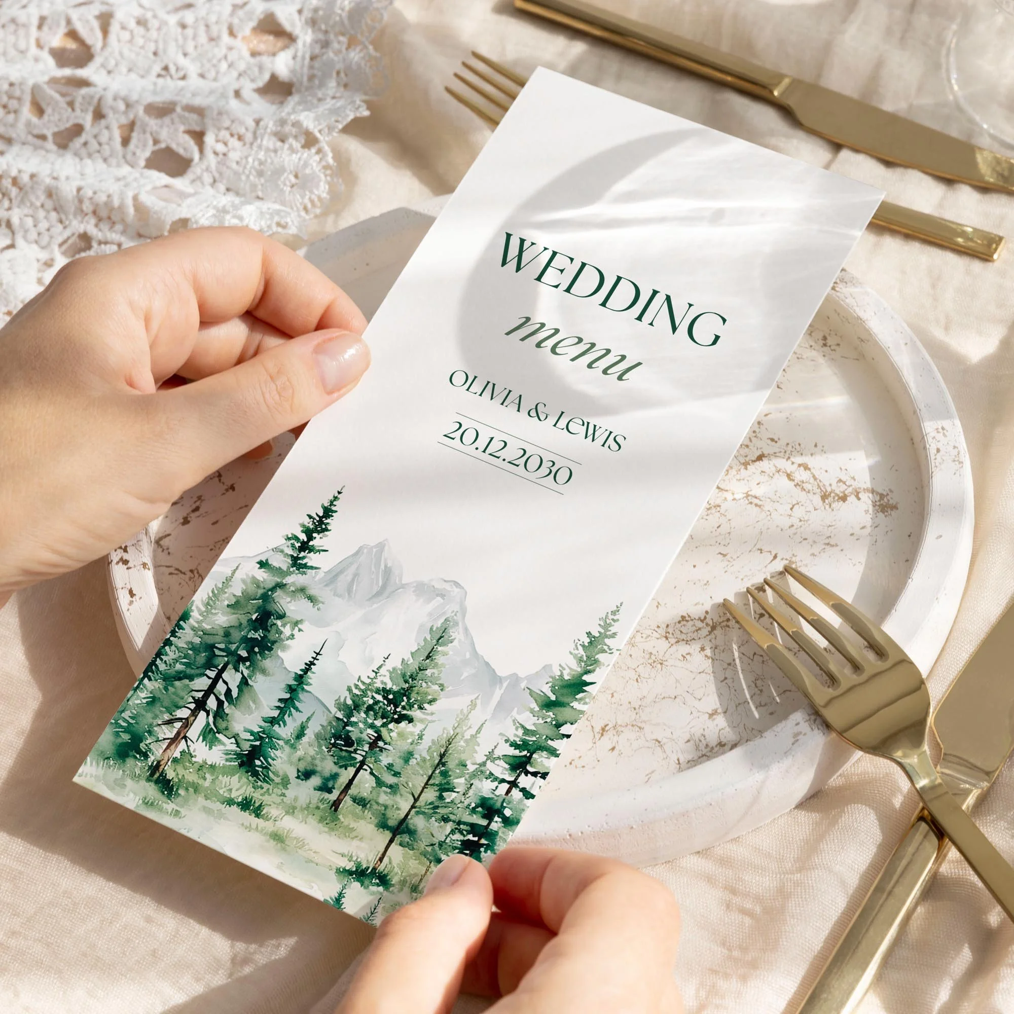 Hand holding an Adventure wedding breakfast menu card with a watercolour pine forest and mountain landscape illustration