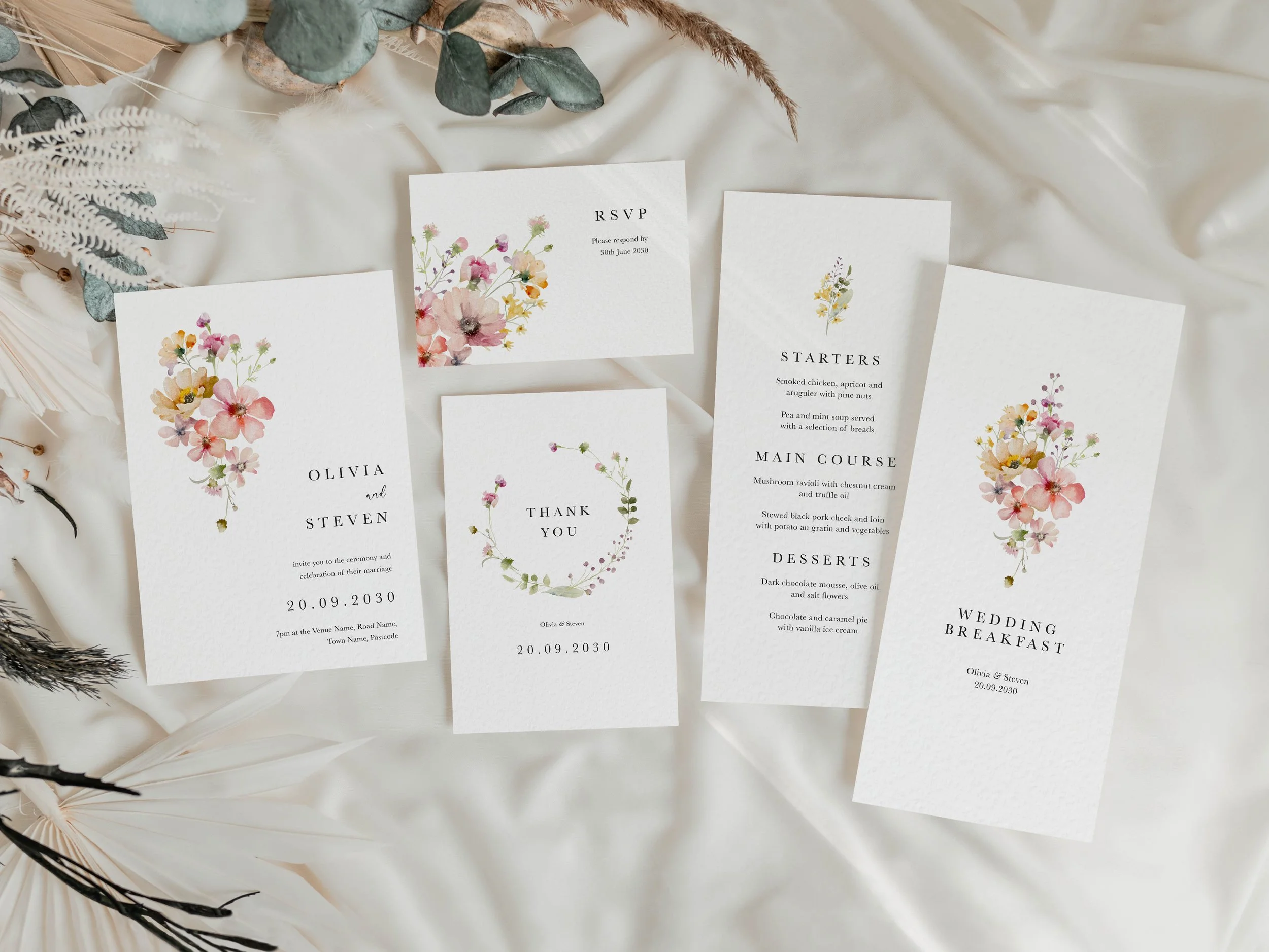 Full Bloom wedding stationery suite flat lay showing invitations, RSVP cards and coordinating pieces with blush pink pastel wildflower design