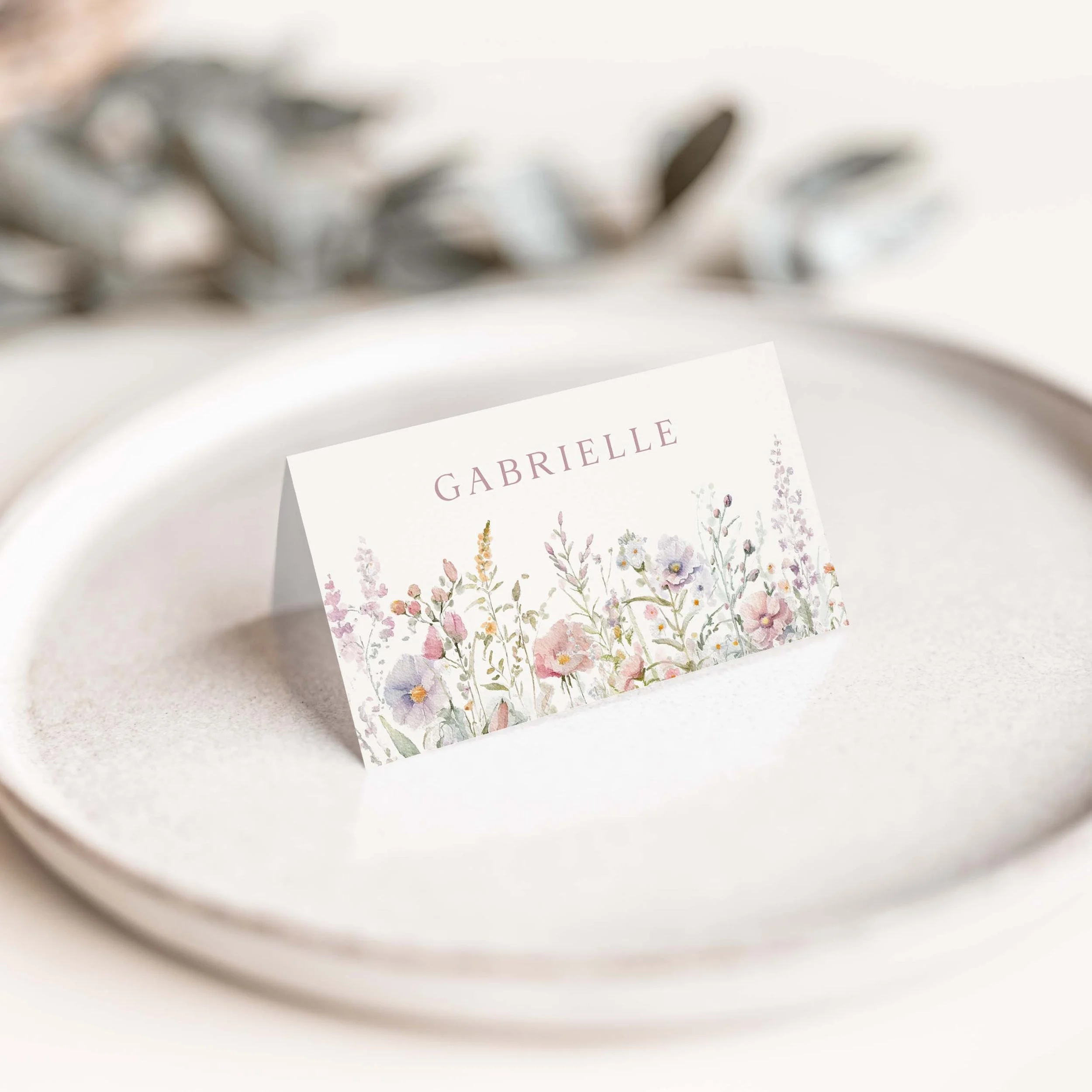 Pastel wildflower wedding place card with floral border along the bottom
