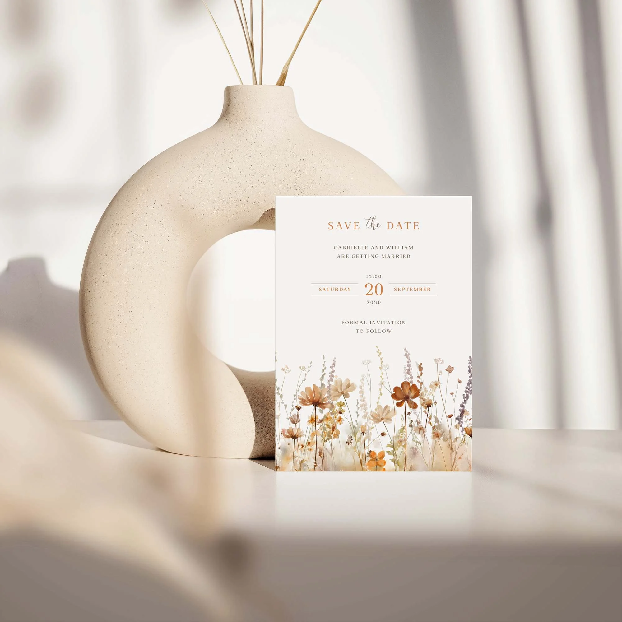 Field Harvest save the date card with autumn wildflower meadow design displayed against a cream ceramic vase on a neutral background