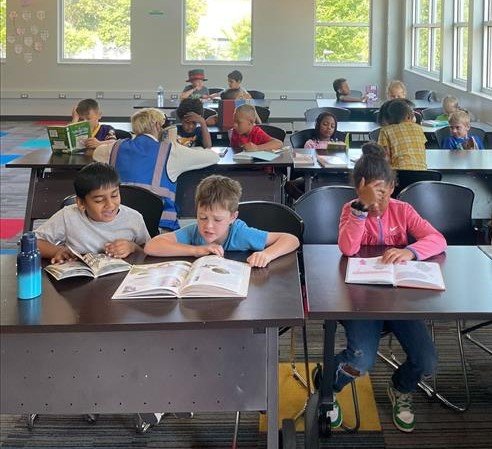 Classroom with young people sitting at desks, reading books and studying.