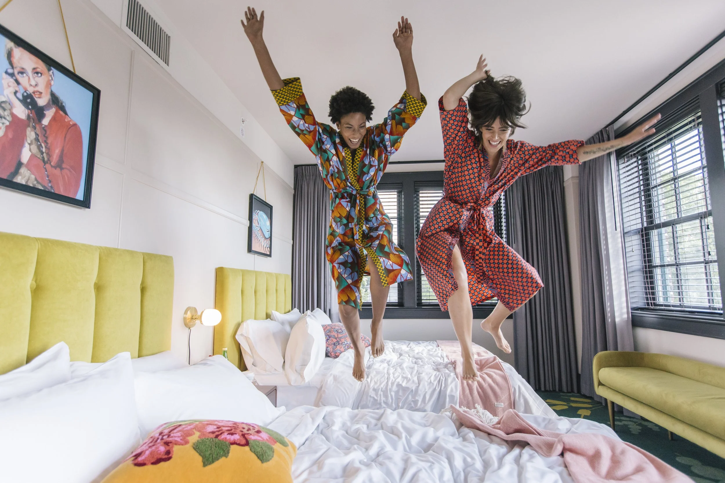 two women jumping on bed