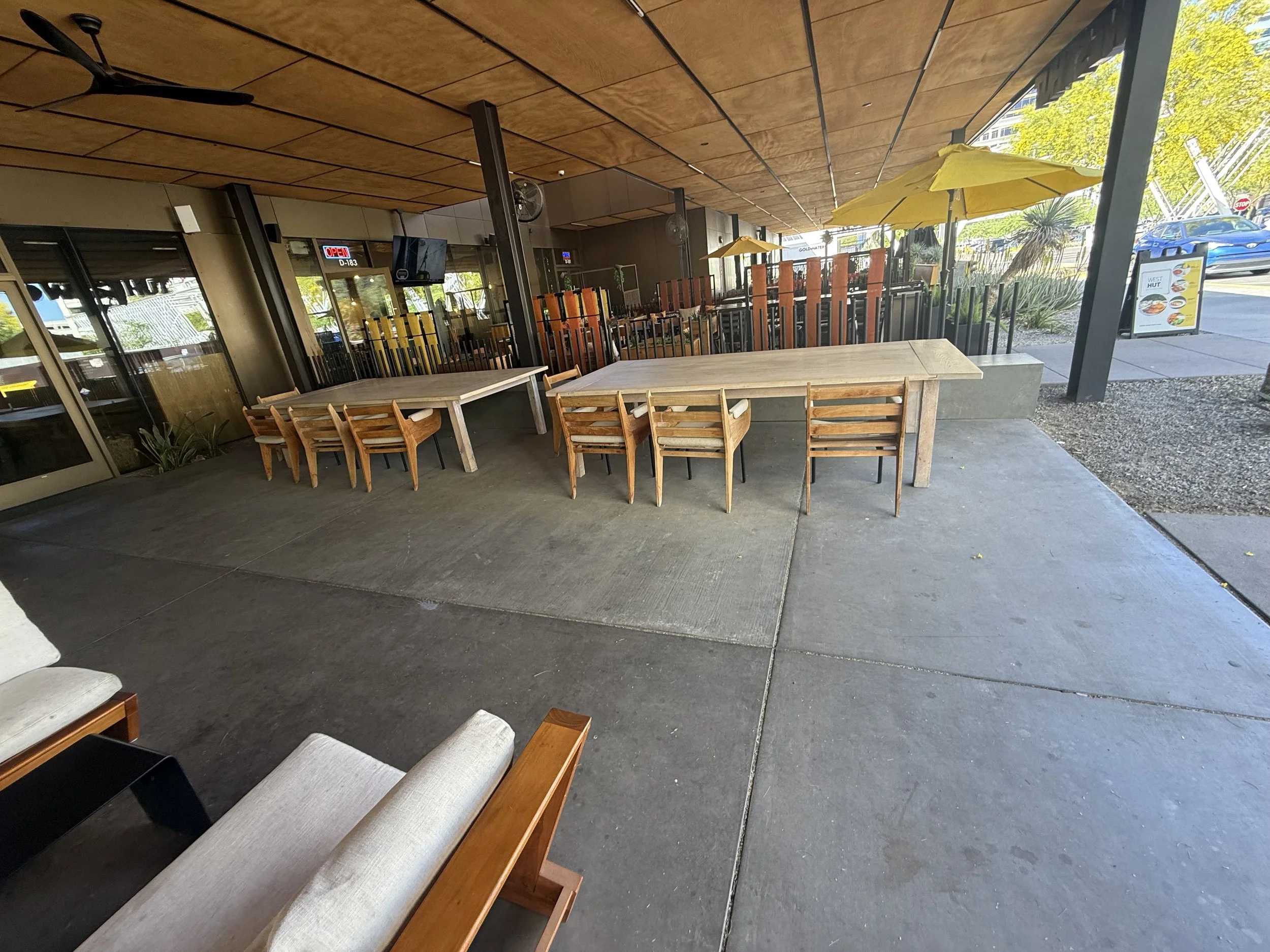 Park Centrals best bar 'The Green Woodpecker' Location of Arcadia Rotary clubs Annual Poker Tournament Empty outdoor patio area with wooden tables, chairs, yellow umbrellas, and a partial view of the indoor restaurant through glass windows.