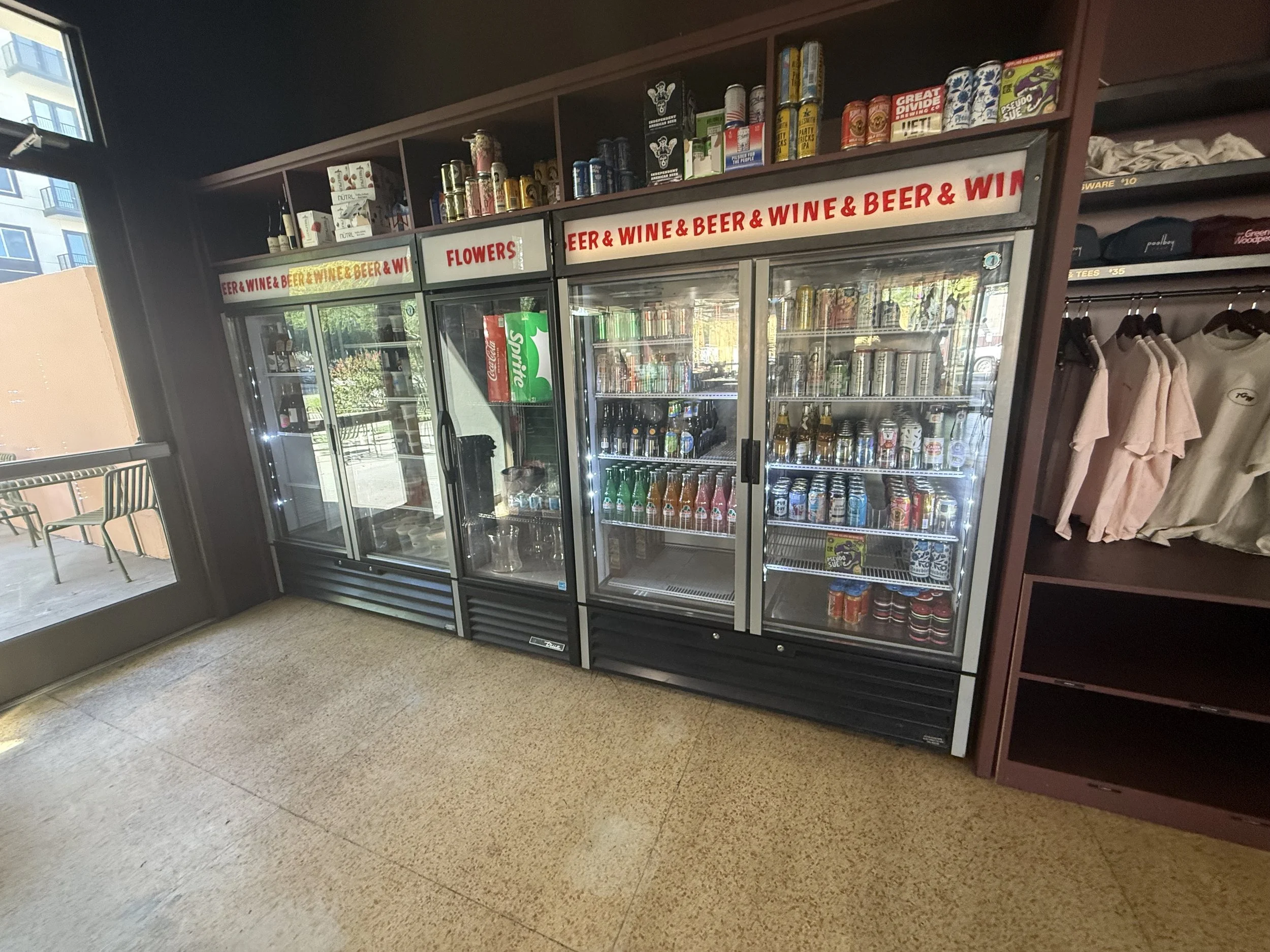 A refrigerated display case containing various cans and bottles of beer and soda. Indoor event space at Park Central in Phoenix, Arizona, where the Phoenix Arcadia Rotary Club hosts its annual poker tournament at The Green Woodpecker venue