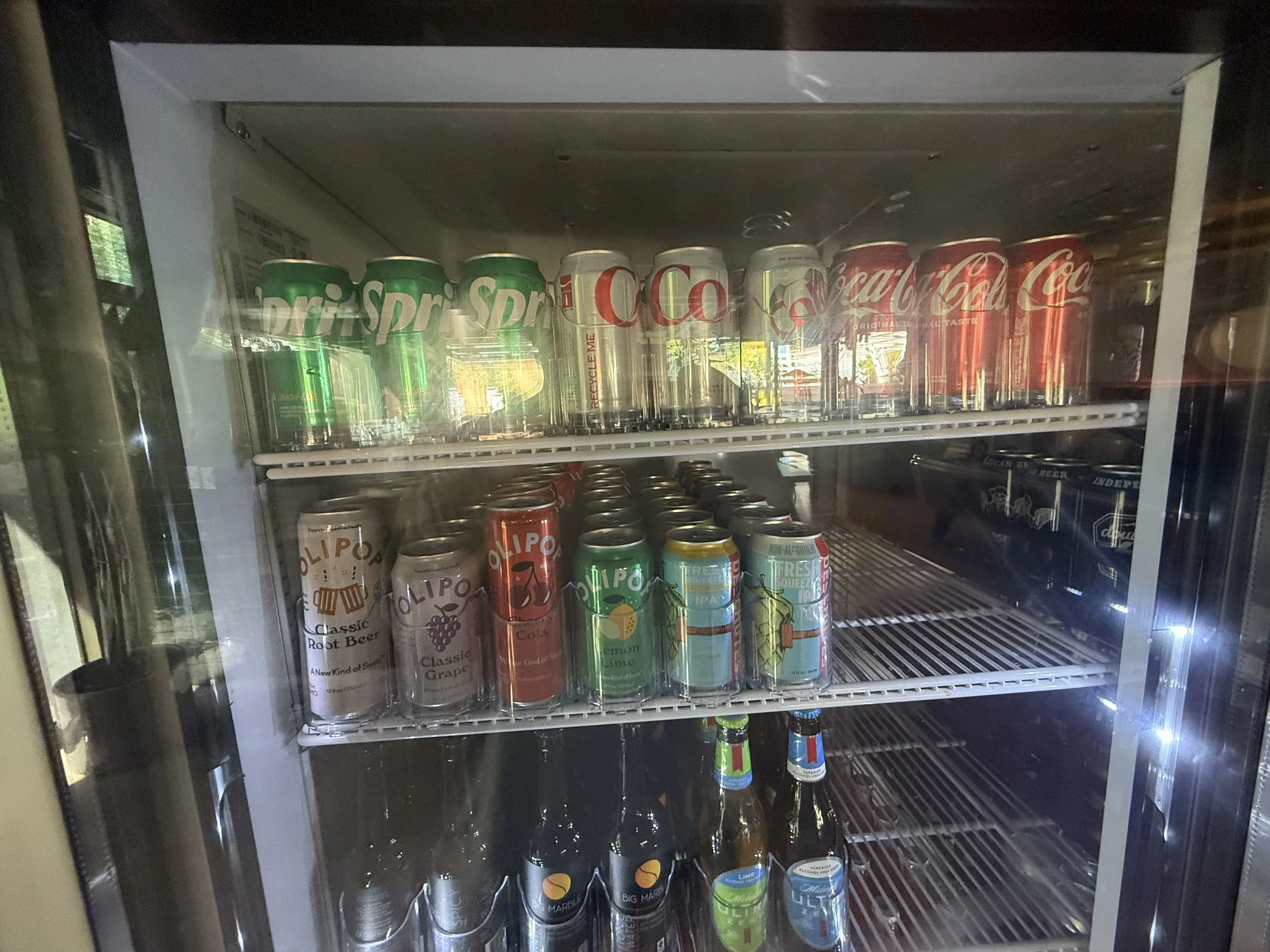 Inside a refrigerated display case with cans of soft drinks, including Sprite, Coca-Cola, and other flavors. “Indoor event space at Park Central in Phoenix, Arizona, where the Phoenix Arcadia Rotary Club hosts its annual poker tournament 
