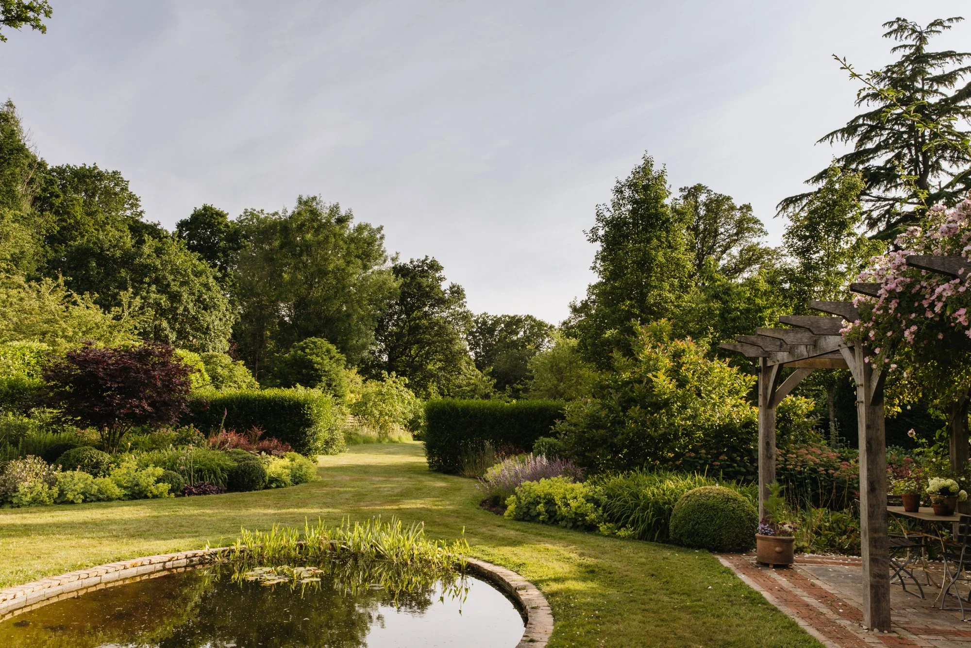 The oval wildlife pond reflects the evening sun and leads the eye to the orchard beyond. 
Photo Eva Nemeth