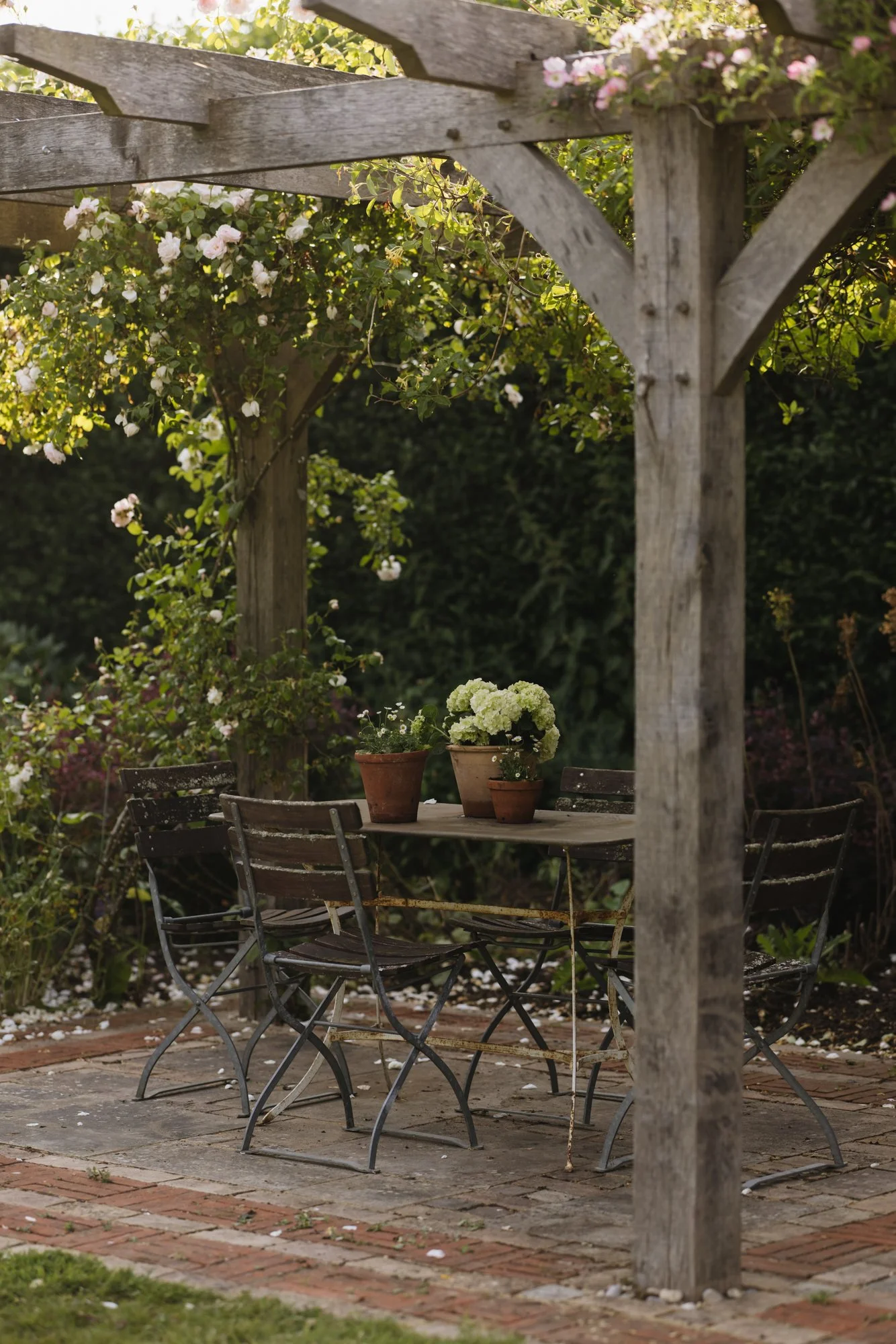 The oak pergola in the main garden is generously covered with climbing roses. The mixed paving of sandstone and brick add a touch of Arts and Crafts detail which ties in the the house. 
Photo Eva Nemeth