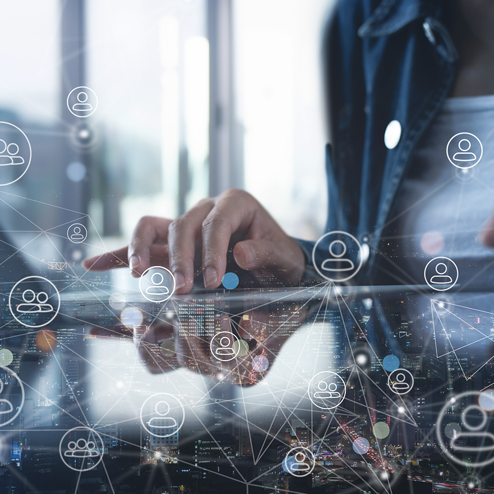 Person using a tablet with digital network icons overlay, representing connectivity and social networking.