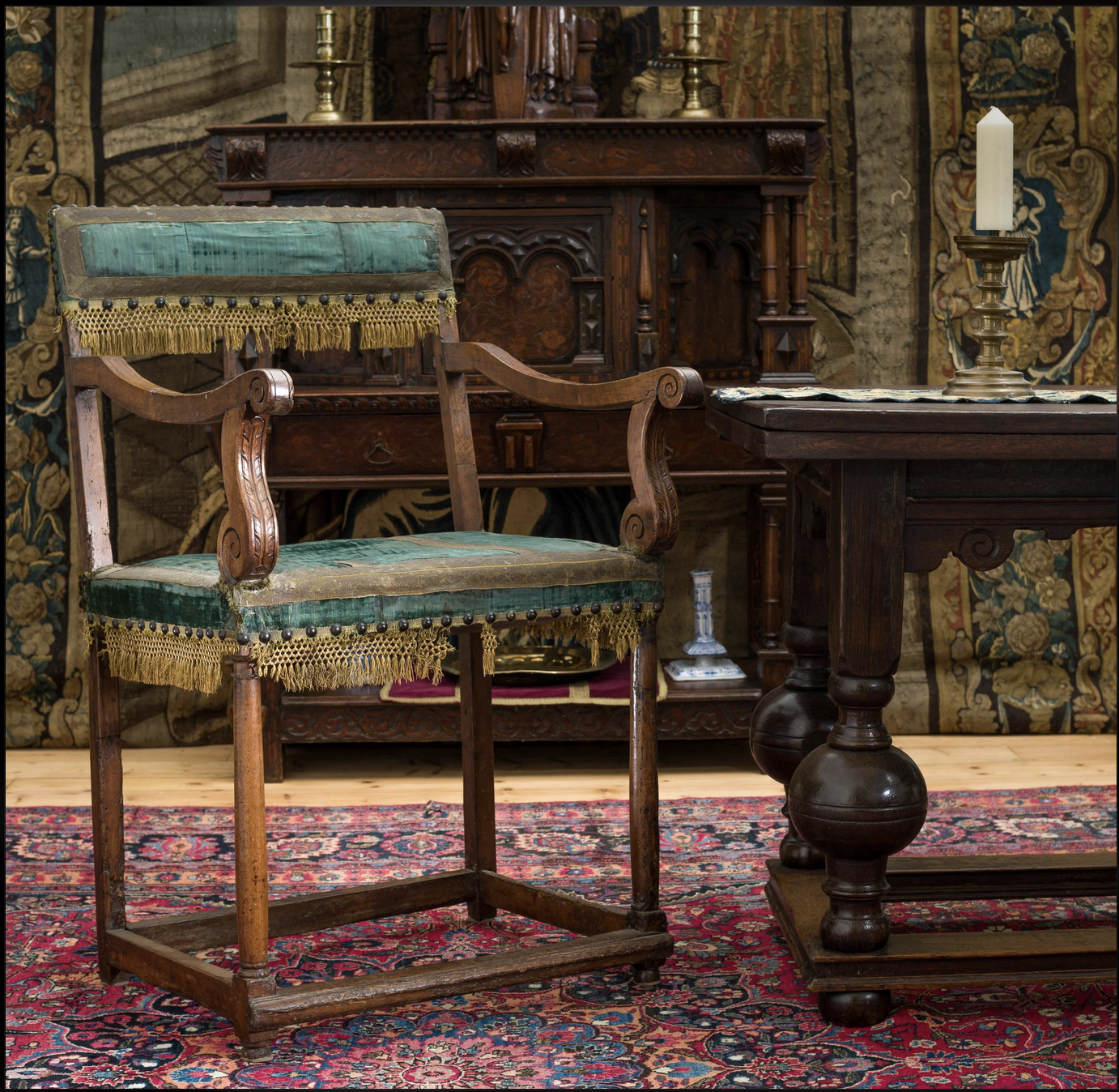 Italian Renaissance Revival armchair with a carved walnut frame, blue velvet upholstery, and decorative fringe, reflecting European craftsmanship and luxury furniture design.