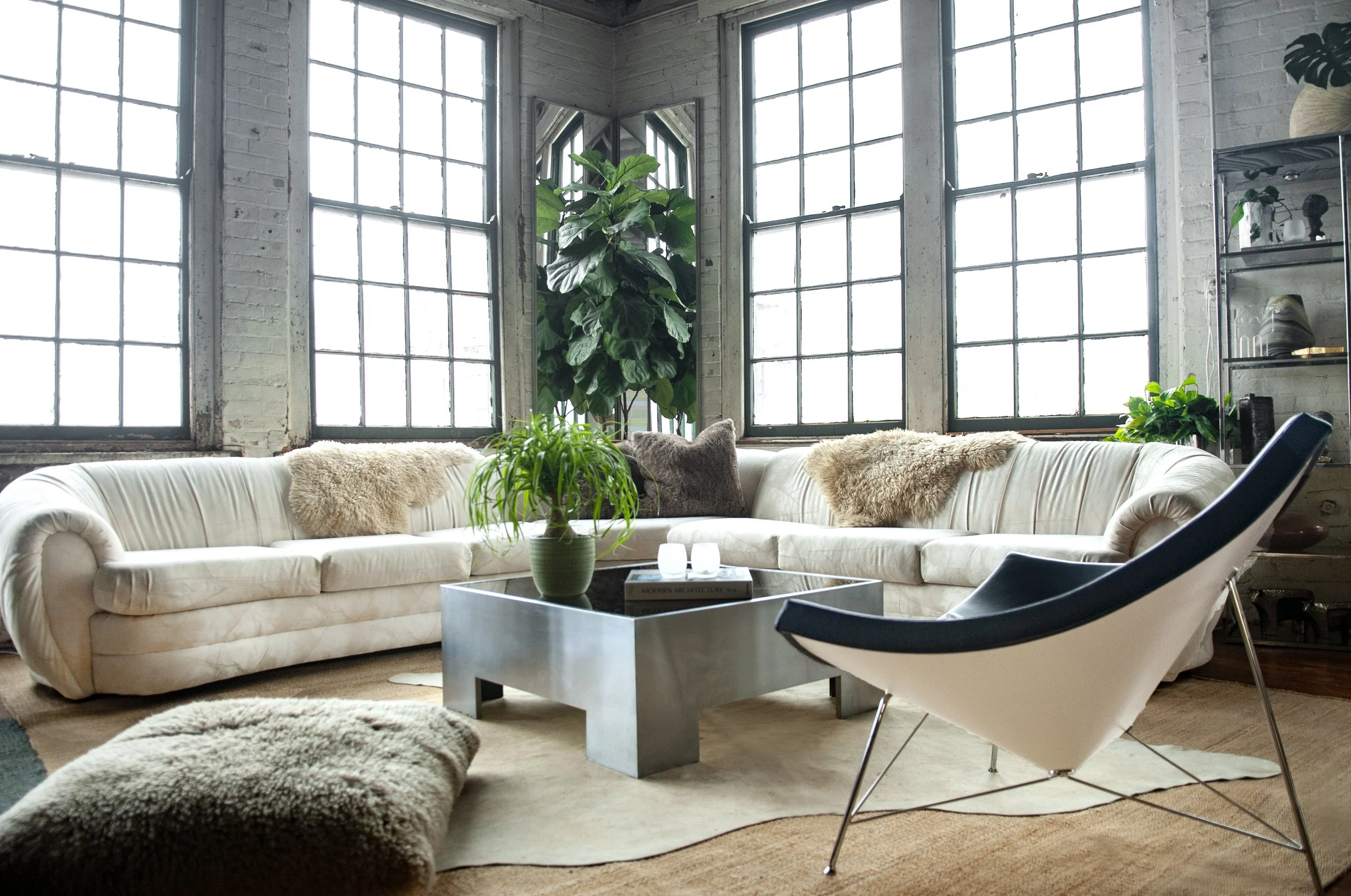 House of No Era's former Camp Washington warehouse studio in Cincinnati, Ohio, featuring a Postmodern Miami coastal-style setup with a Vladimir Kagan sculptural sectional sofa, George Nelson's Coconut Chair by Vitra, and a Paul Mayen aluminum low-slu