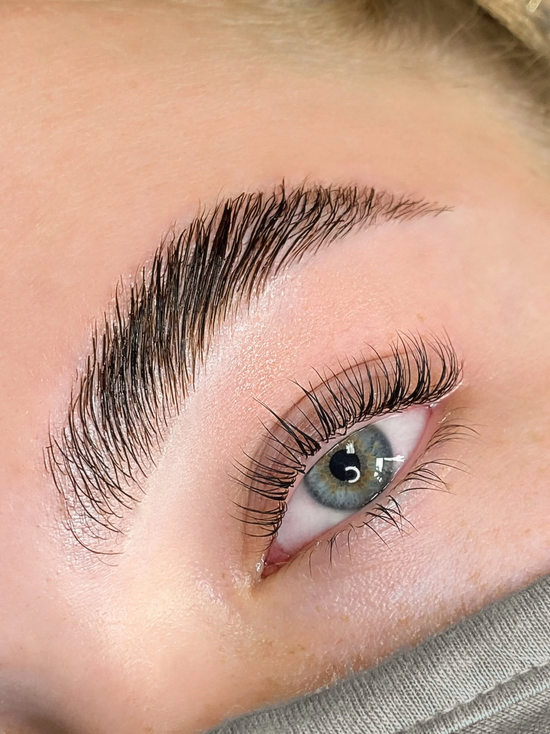 Close-up of a person's eye with long, curled eyelashes and well-groomed eyebrow.