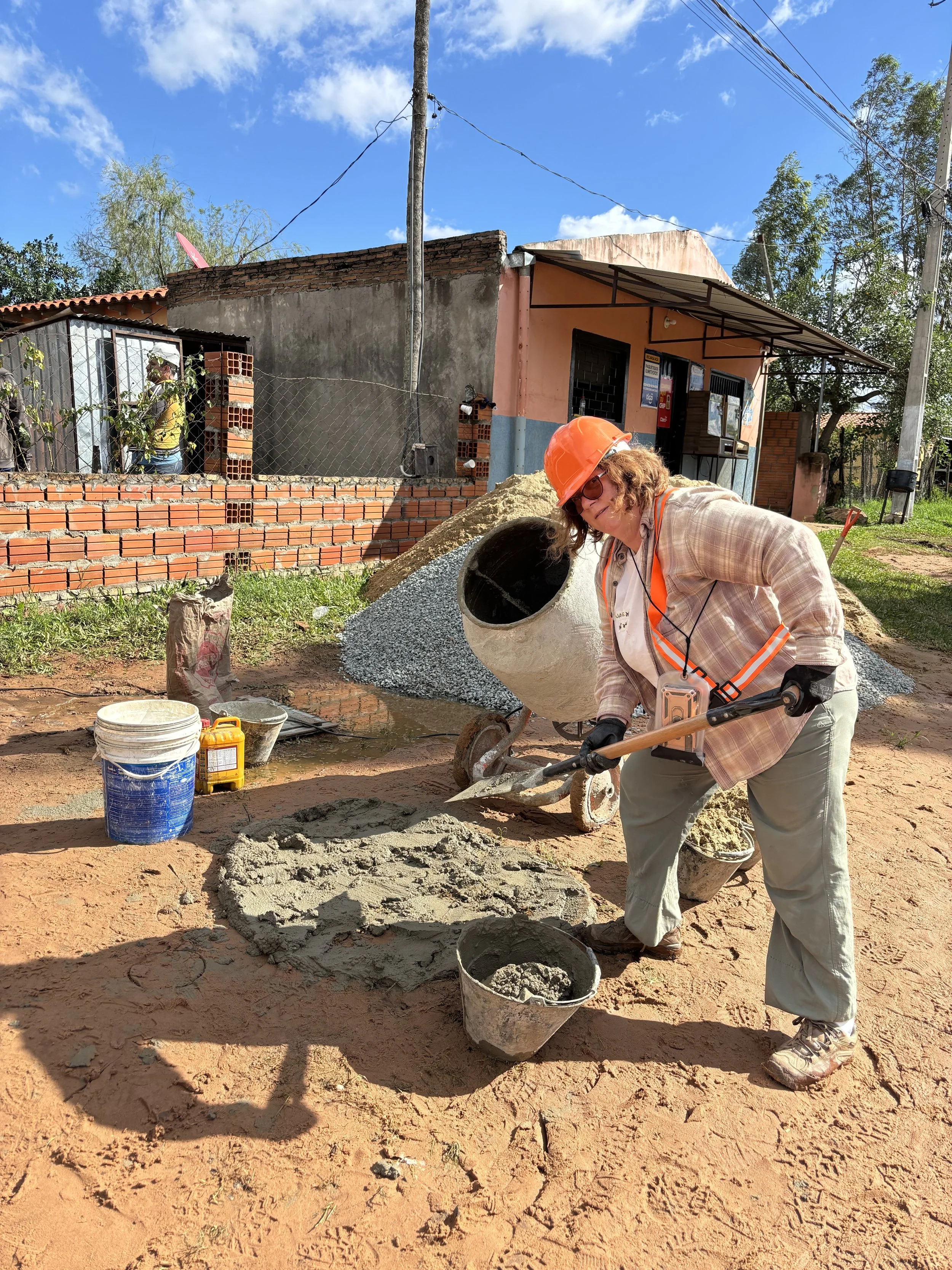 Woman in a hard hat shovels cement