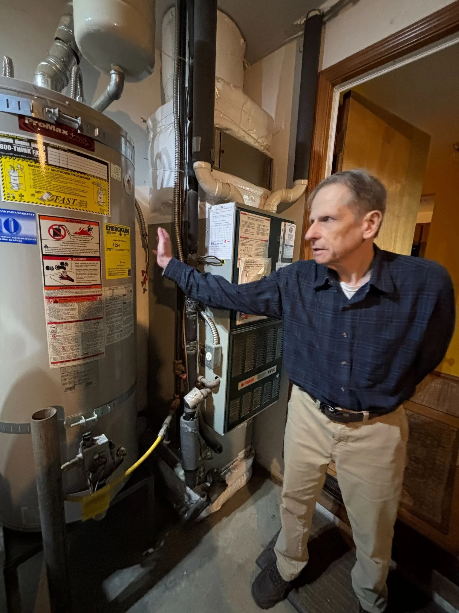An elderly homeowner stands next to his new water heater