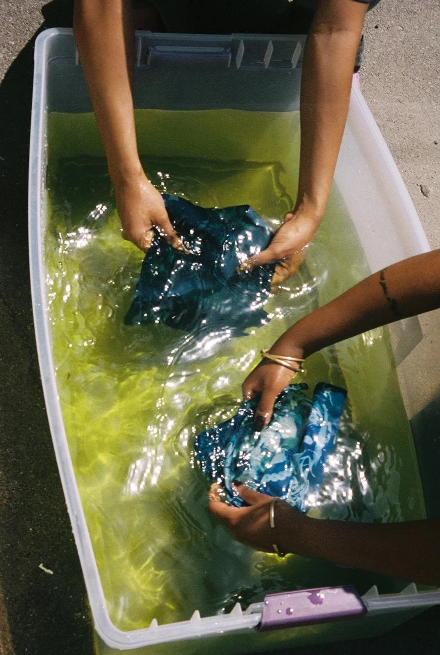Workshop participants wash their cyanotype photograms in water to reveal the final image. Photo by Marvin James for Its-in-Scope.
