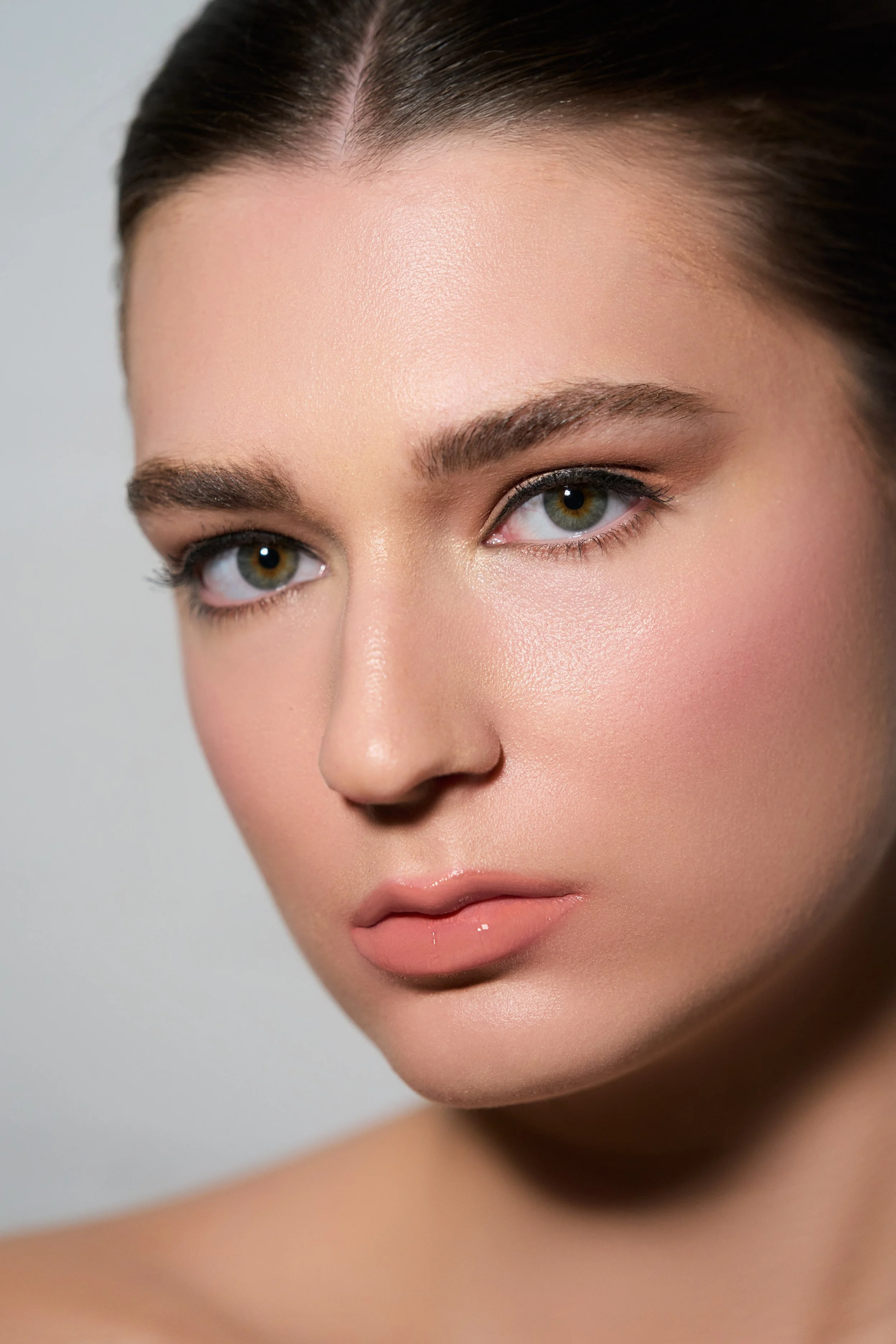 Close-up of a woman's face showing her blue eyes, full lips, and smooth skin.