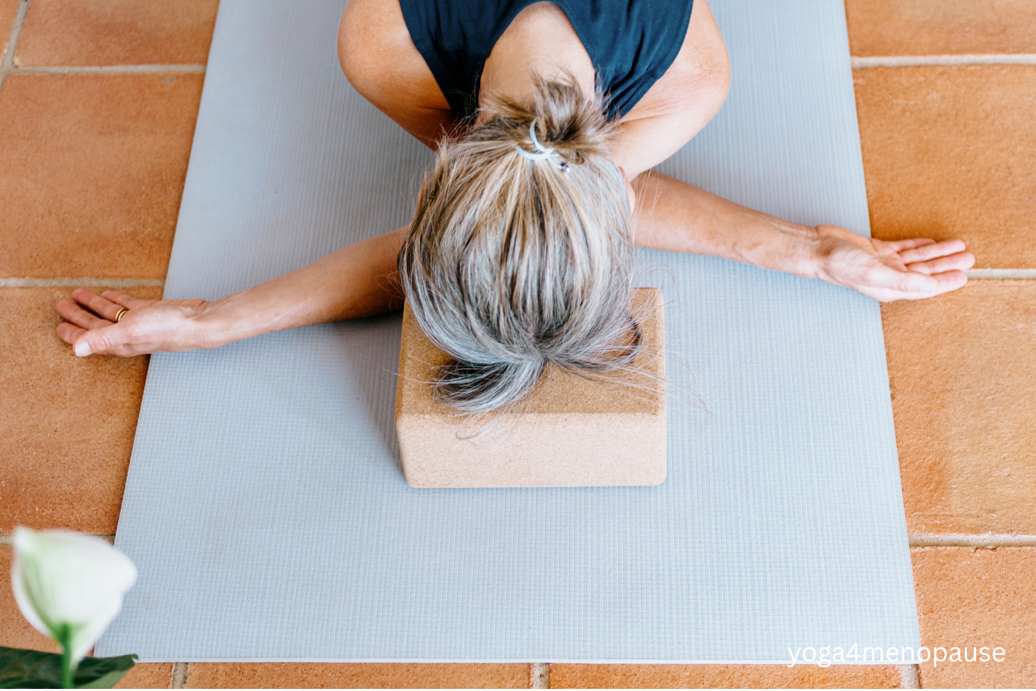 donna in menopausa in una posizione yoga di riposo con testa appoggiata ad un blocco