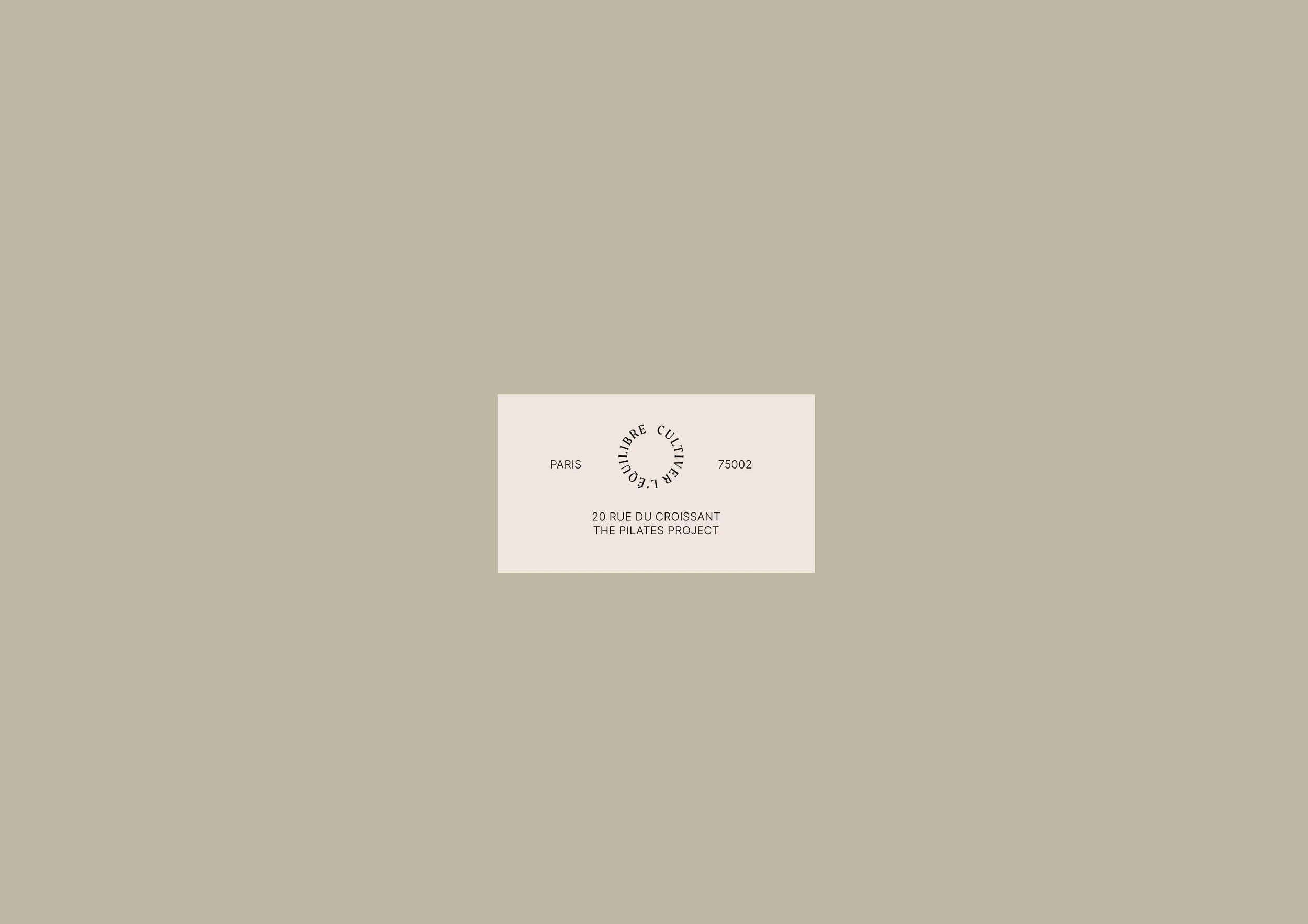 A business card with the address '20 Rue du Croissant, The Pilates Project' in Paris, France, on a beige background.