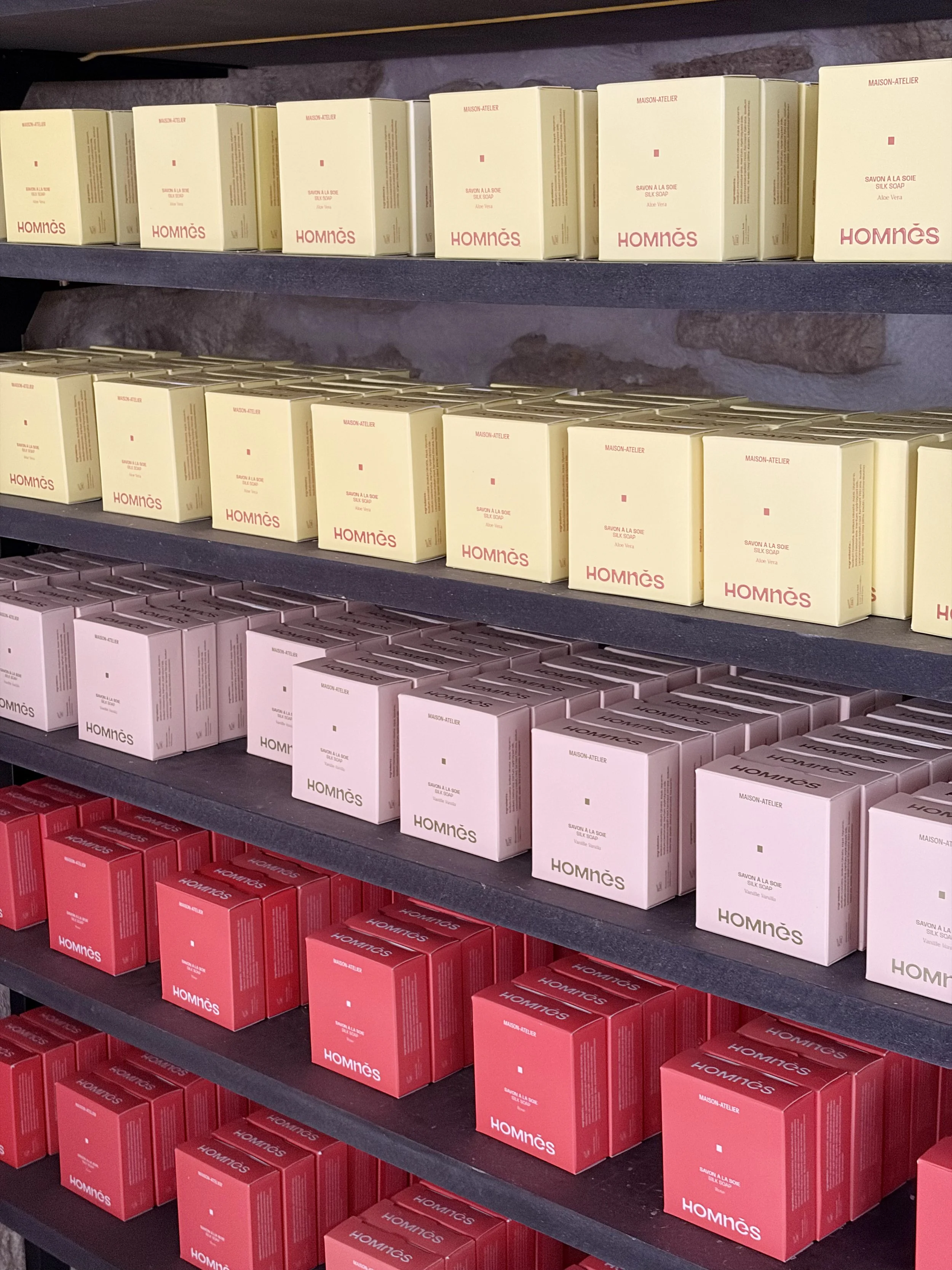 Shelves filled with boxes of HOMNÈS soap in yellow and red packaging.
