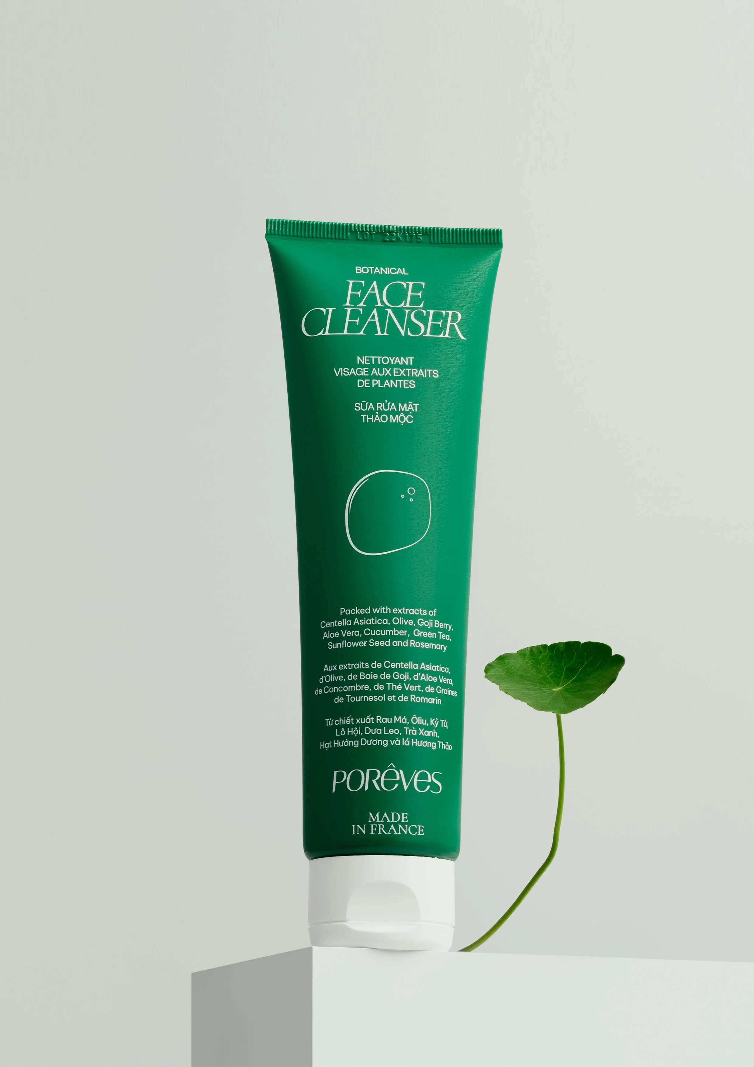 Un tube vert de nettoyant visage de la marque Porêves designé par le studio impulso posé sur une surface blanche, avec une feuille verte à côté, sur un fond neutre.
