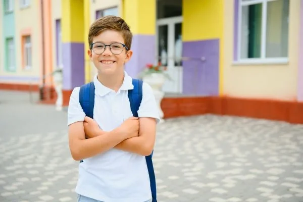 A smiling young boy in a school hallway.