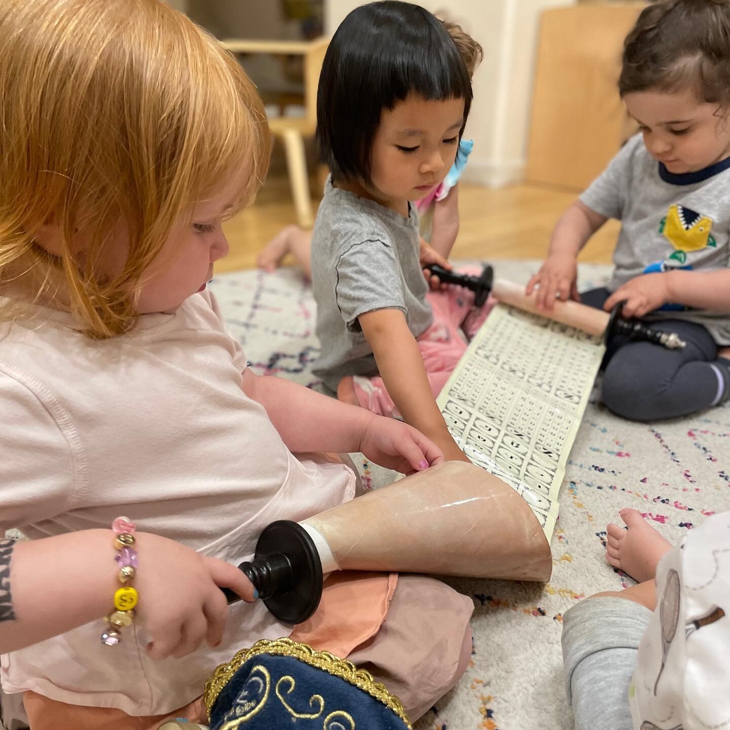 Our campers in the Blossoms class especially love engaging in Jewish learning through Tefillah time every day and our pre-Shabbat celebration each Friday! Here they are exploring a play Torah during open center time. The scroll format makes it an esp