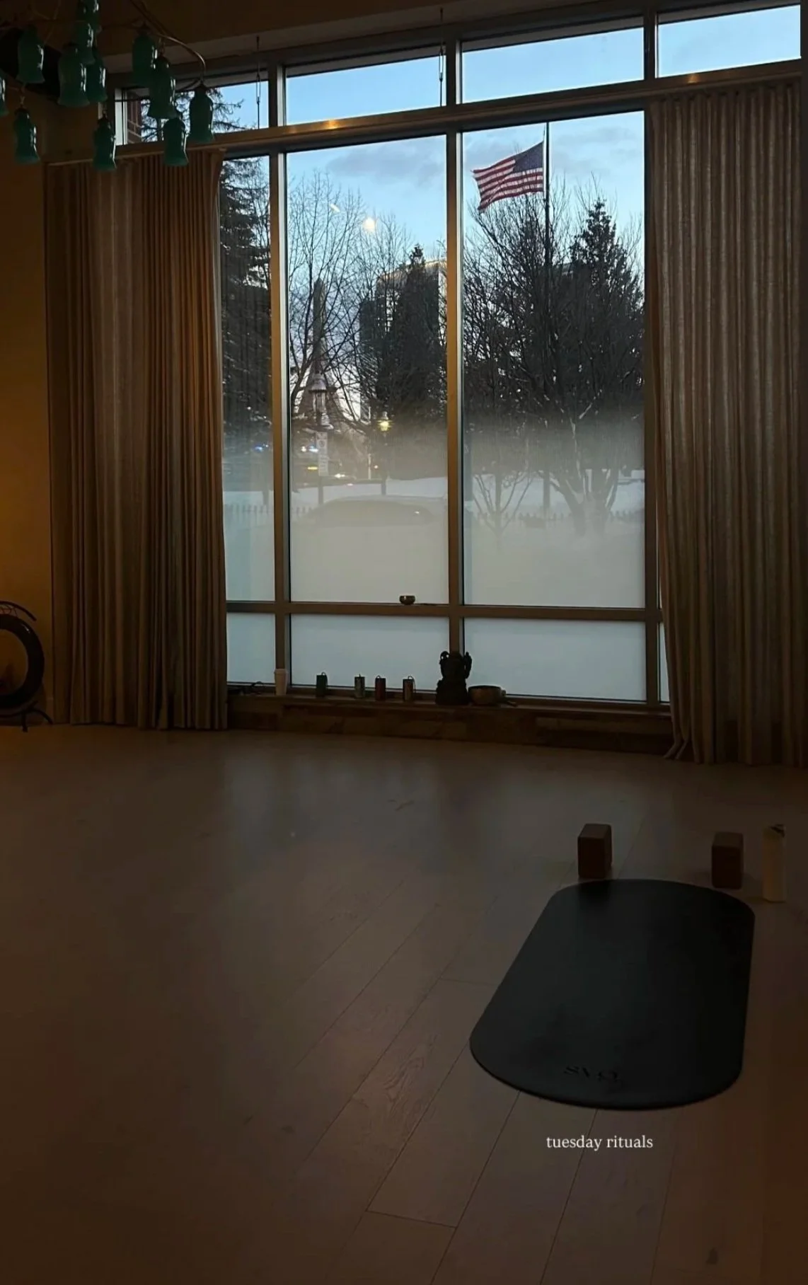 A shot of the negro mate capsula mat laid out on the hardwood floor during an evening restorative class.