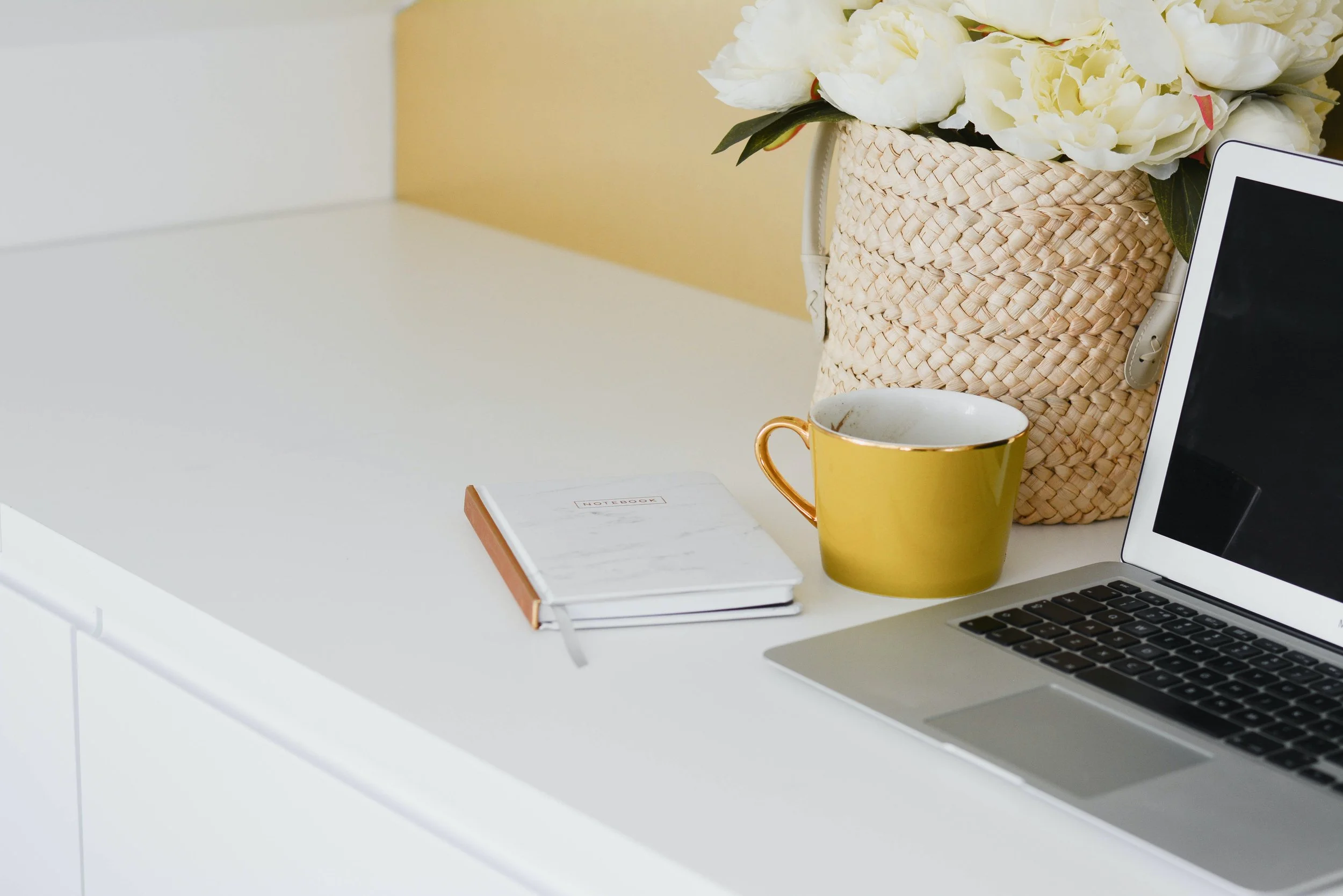 Home Office Workspace with Yellow Ceramic Mug and Flowers