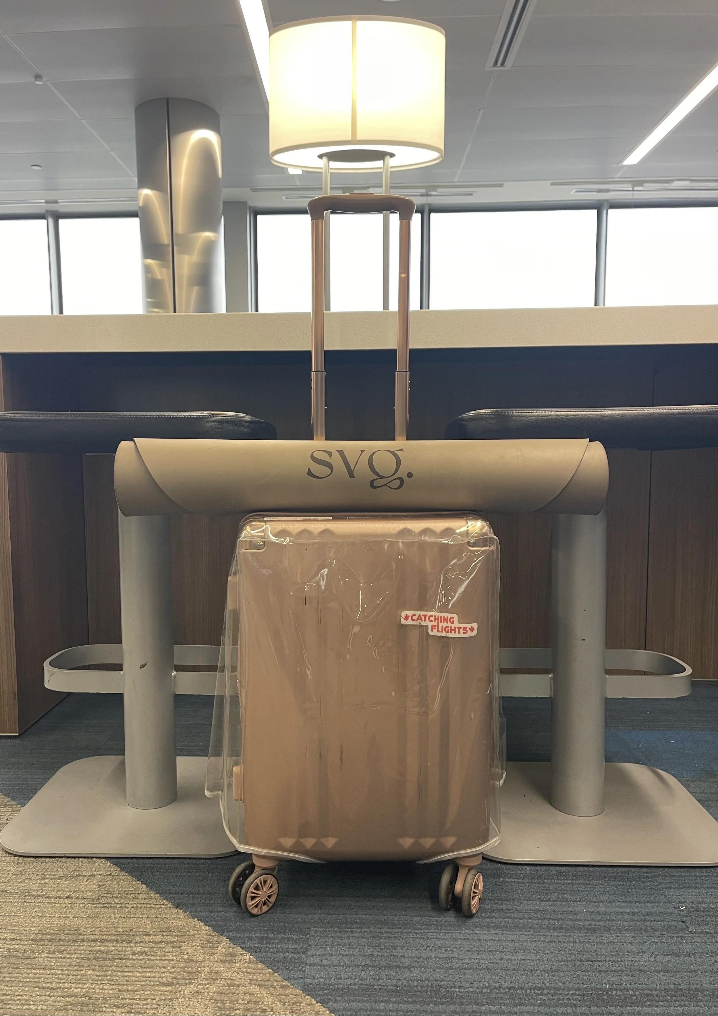 the perla de leche capsula mat rolled up on top of a carry-on luggage at the airport lounge.