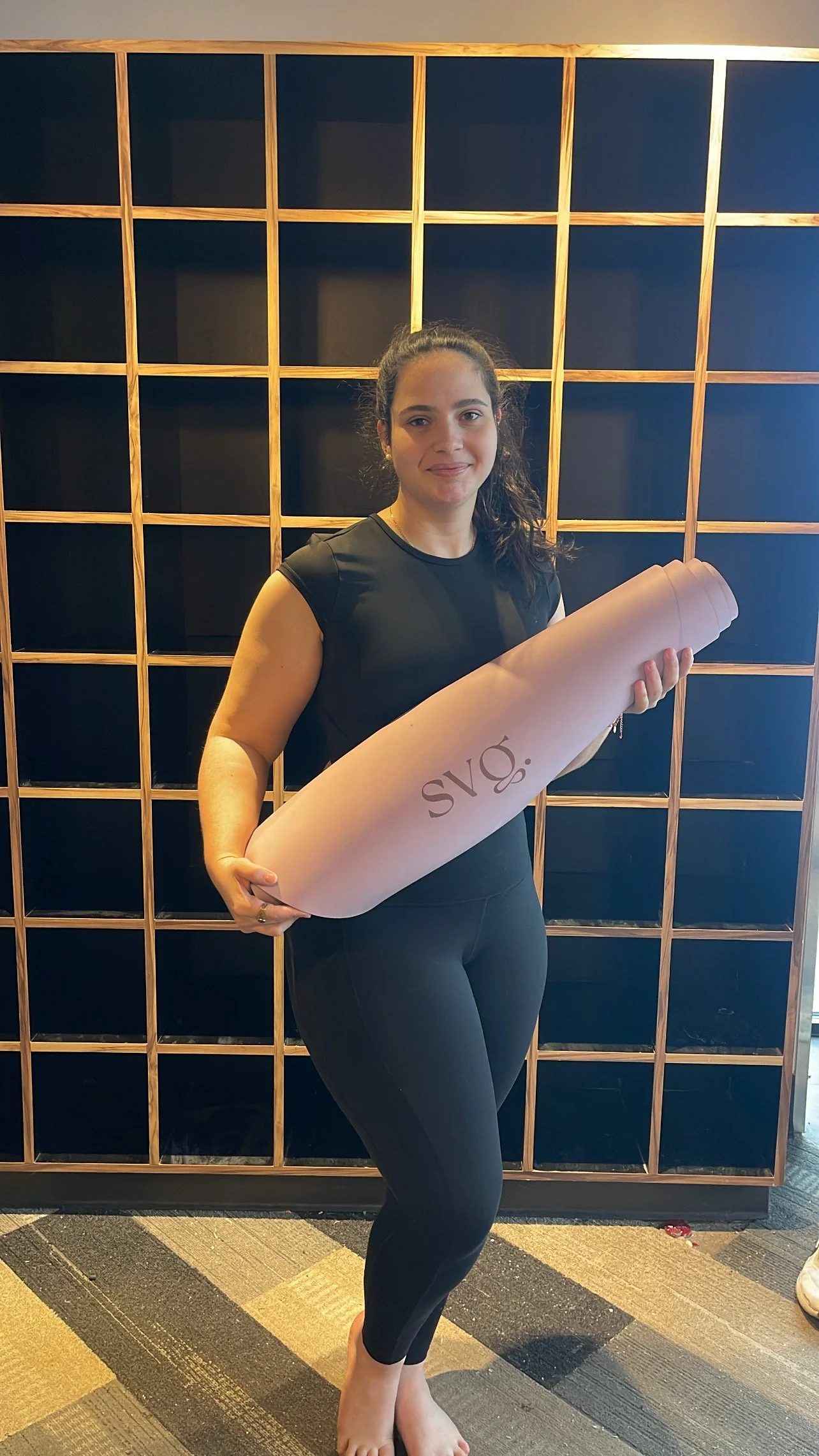 A woman holding her lila serena capsula mat in her hands.